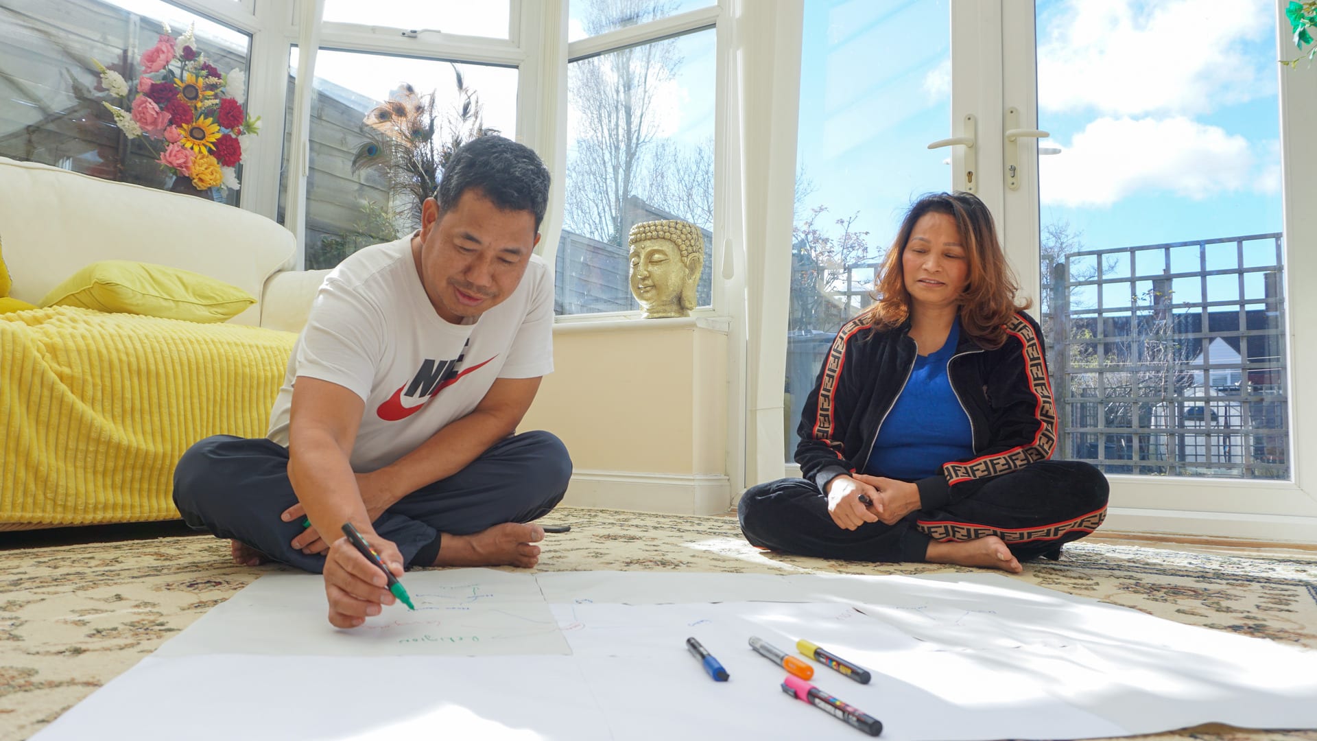 Ashmina's father and mother mindmapping sat on the floor in their conservatory.