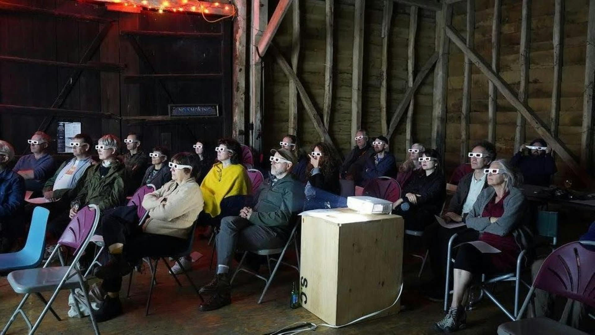 A seated audience watching a film with 3D glasses