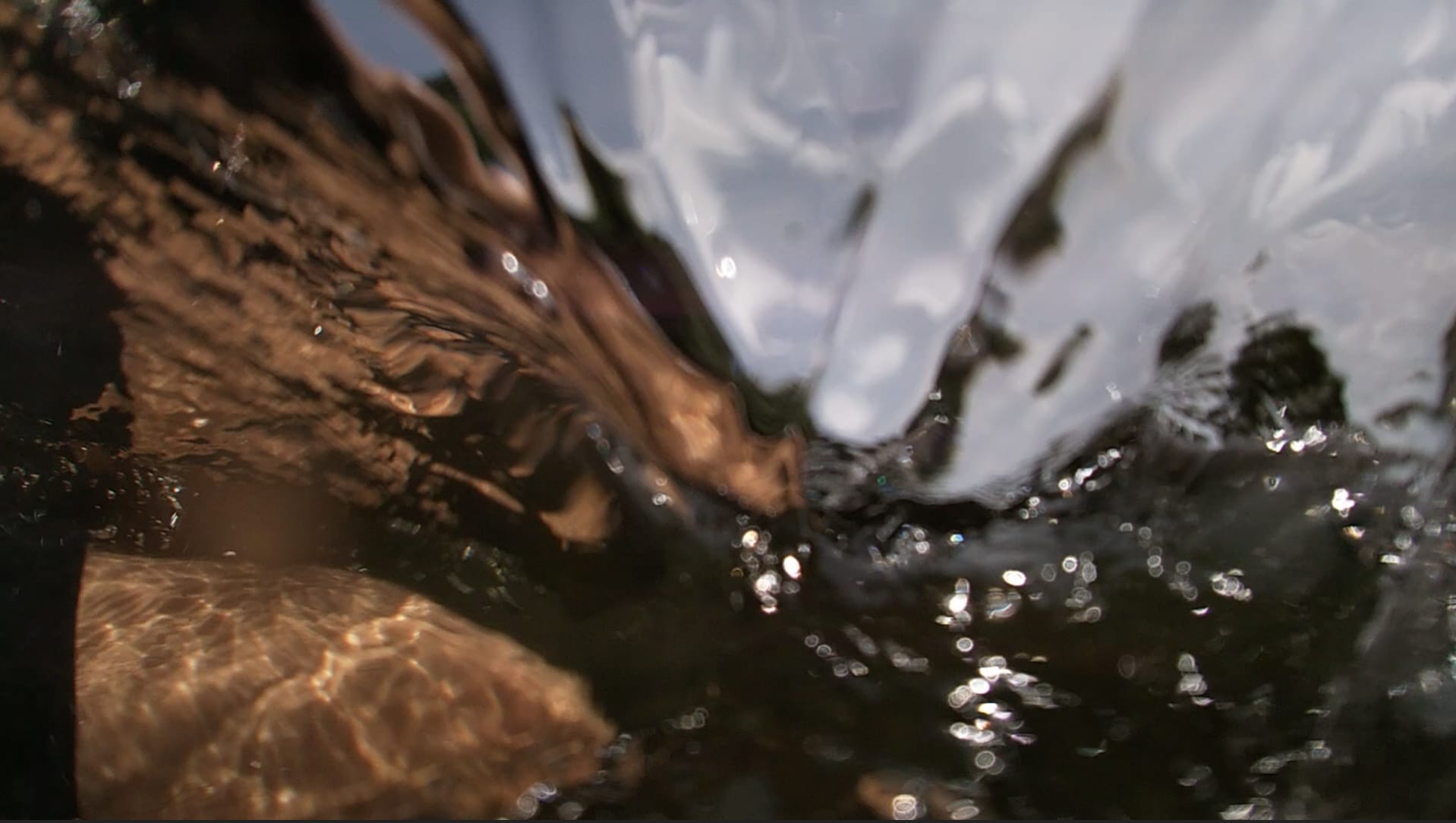 a blurry image showing someone crouching in the water as it washes over their leg