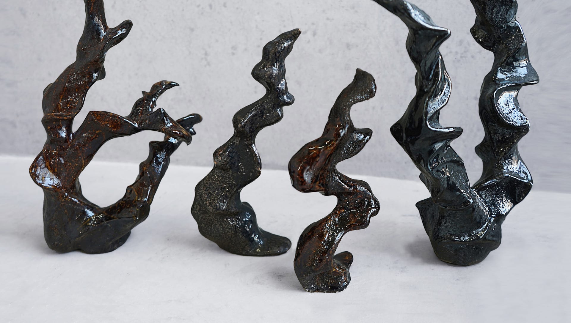 A group of fluid sculptures with dark mirror glazes