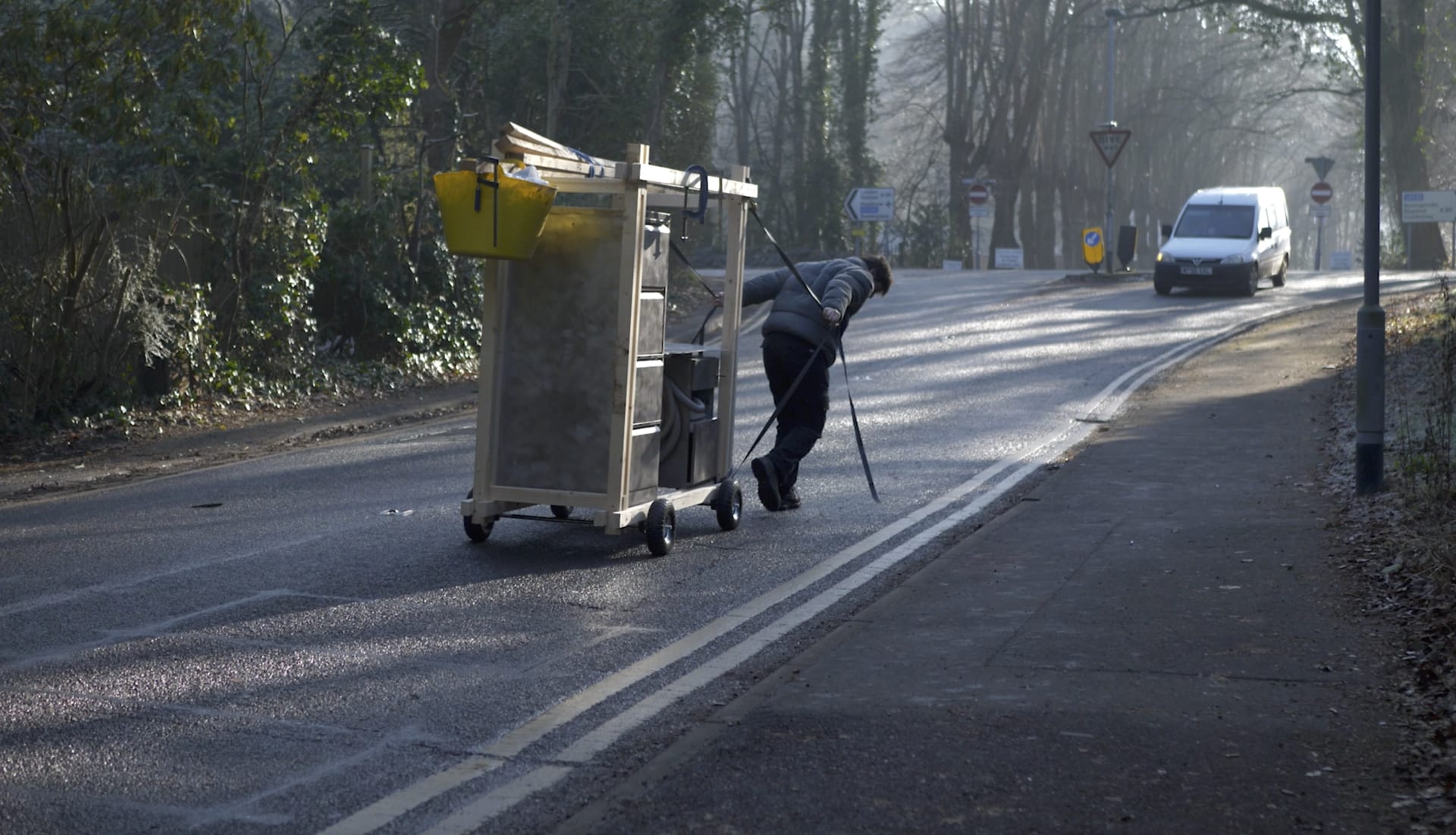 Man dragging workshop cart on busy road