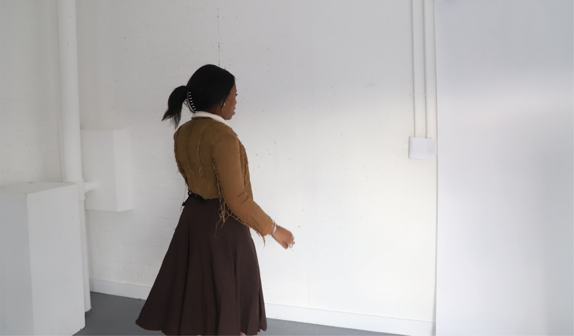 a model wearing a light brown women jacket with frayed edges.