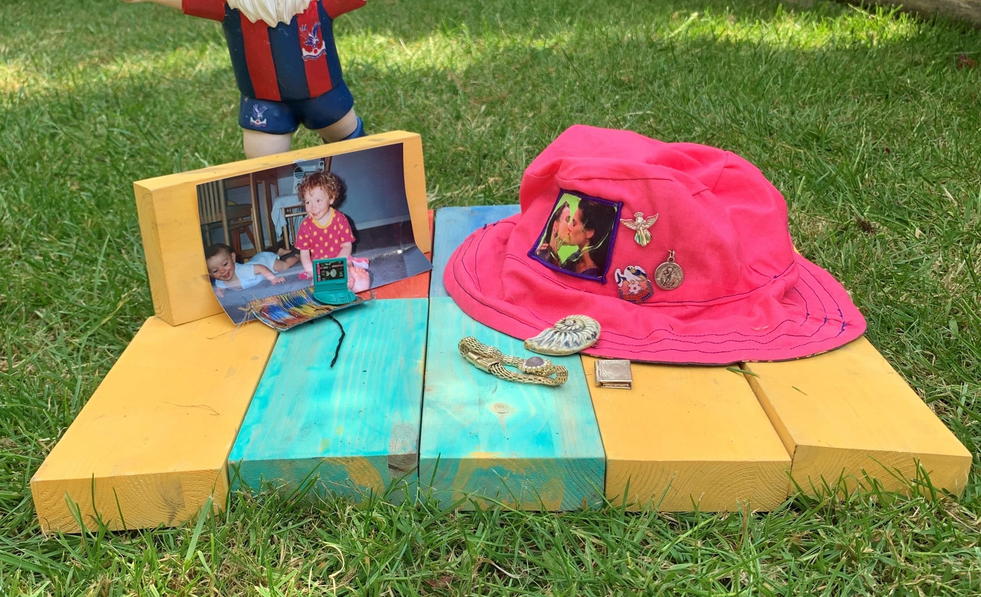 A collection of objects on painted wooden blocks, a hat and photographs from early childhood