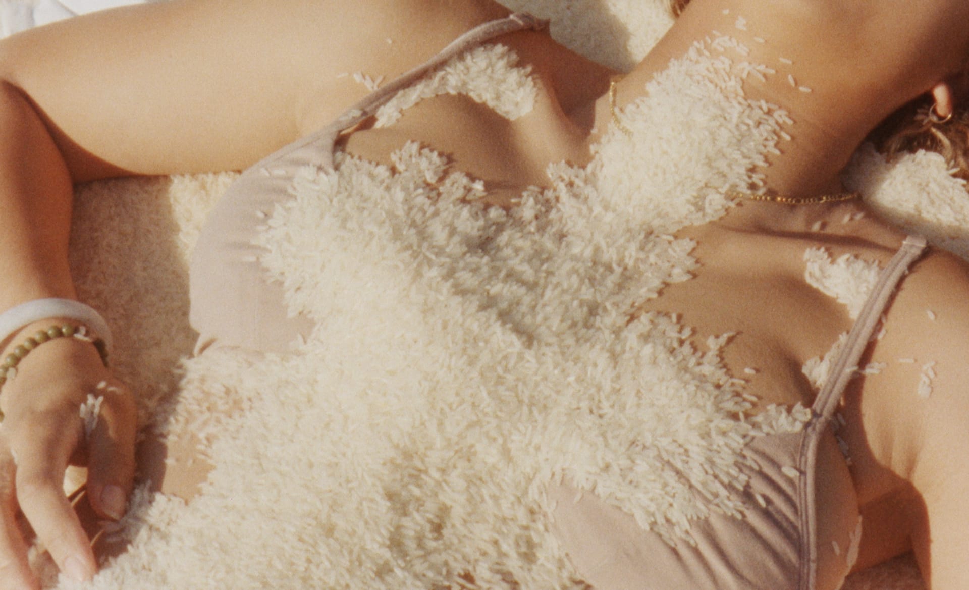 A light brown woman's chest covered in rice