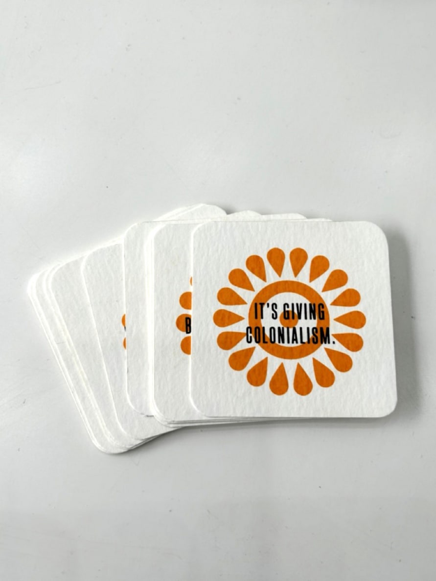 Black text in capitals, upon an orange floral symbol on square white cards