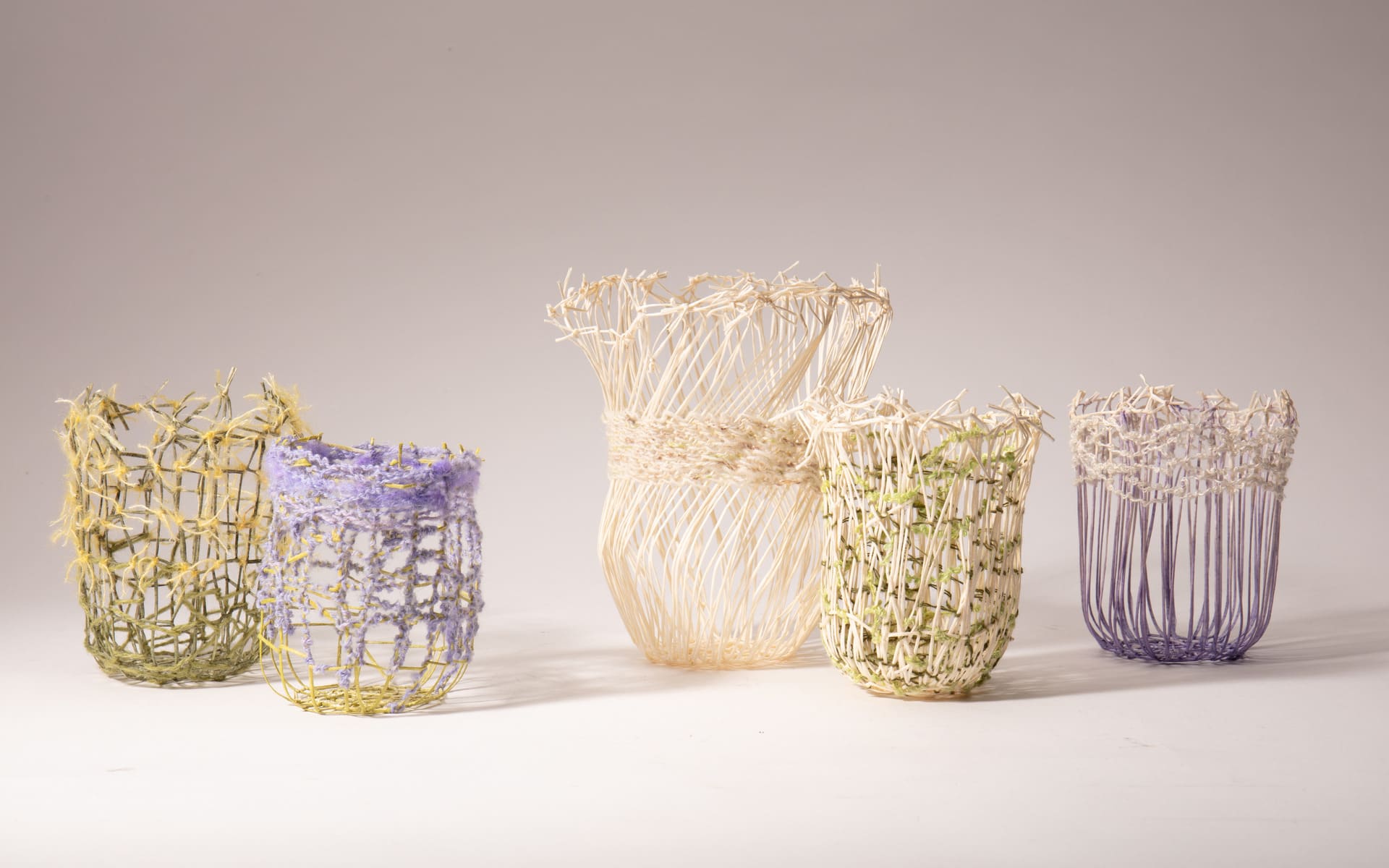 A group of five vessels are shown against a white background. The vessels are a mix of green, white, yellow and purple tones.