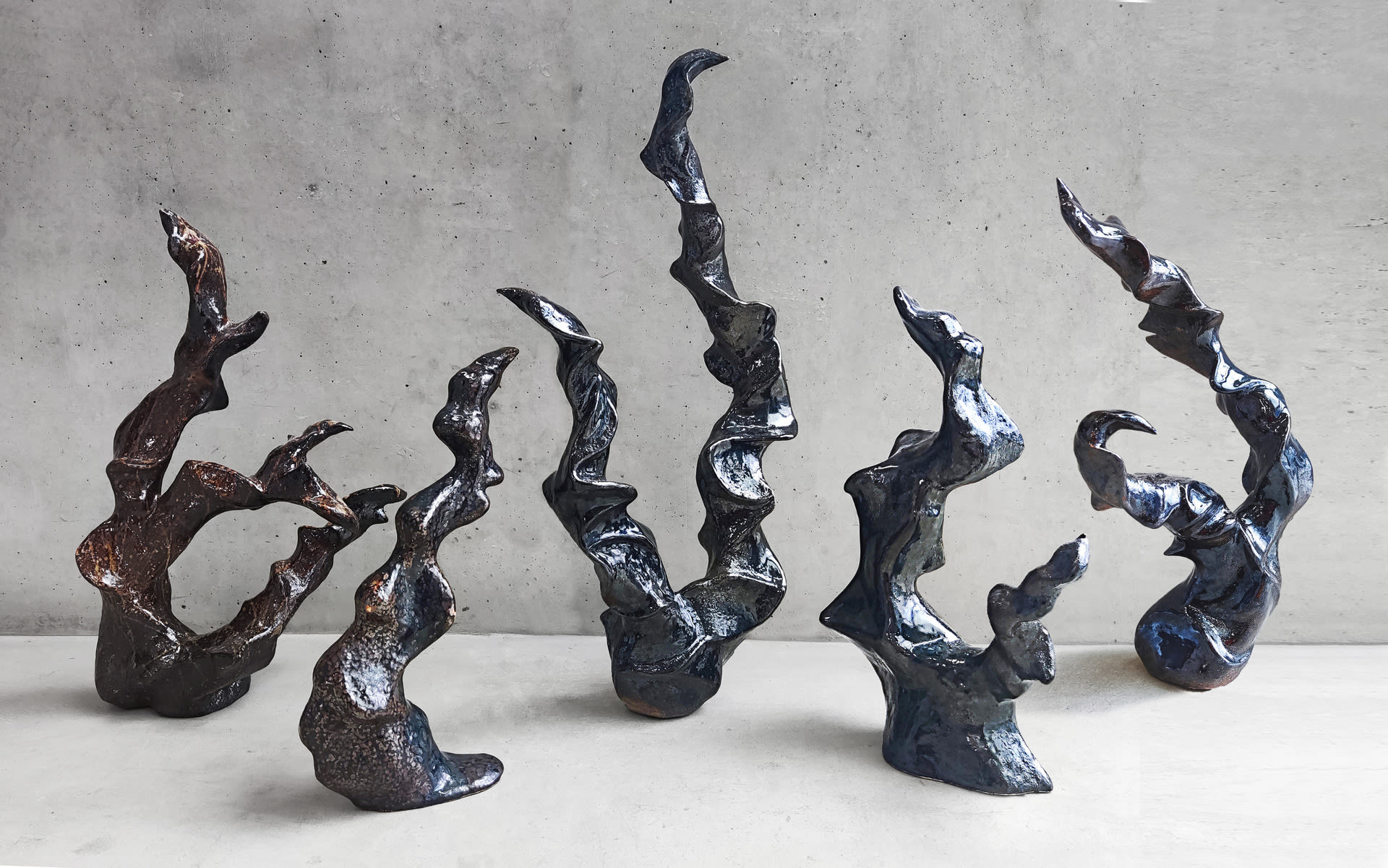 A group of fluid sculptures with dark mirror glazes