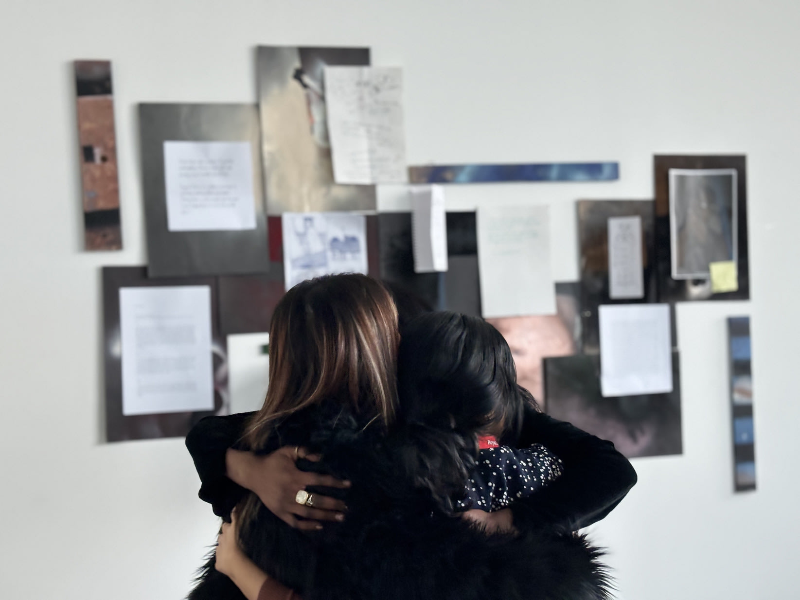 Three students in a hug in front of the displayed letters at the exhibition.