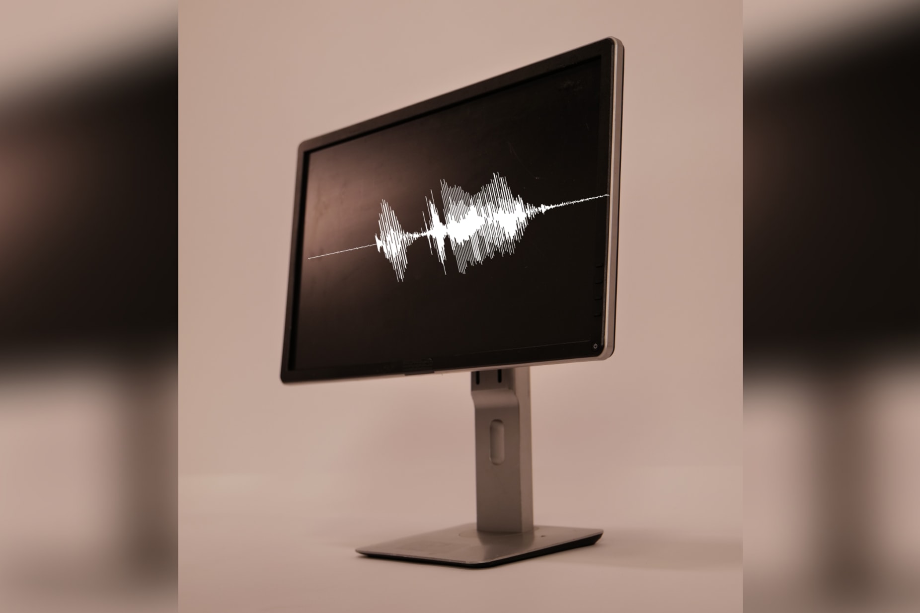 Standing big and bold like a monolith on a neutral background, a monitor displays a white waveform against its black screen.