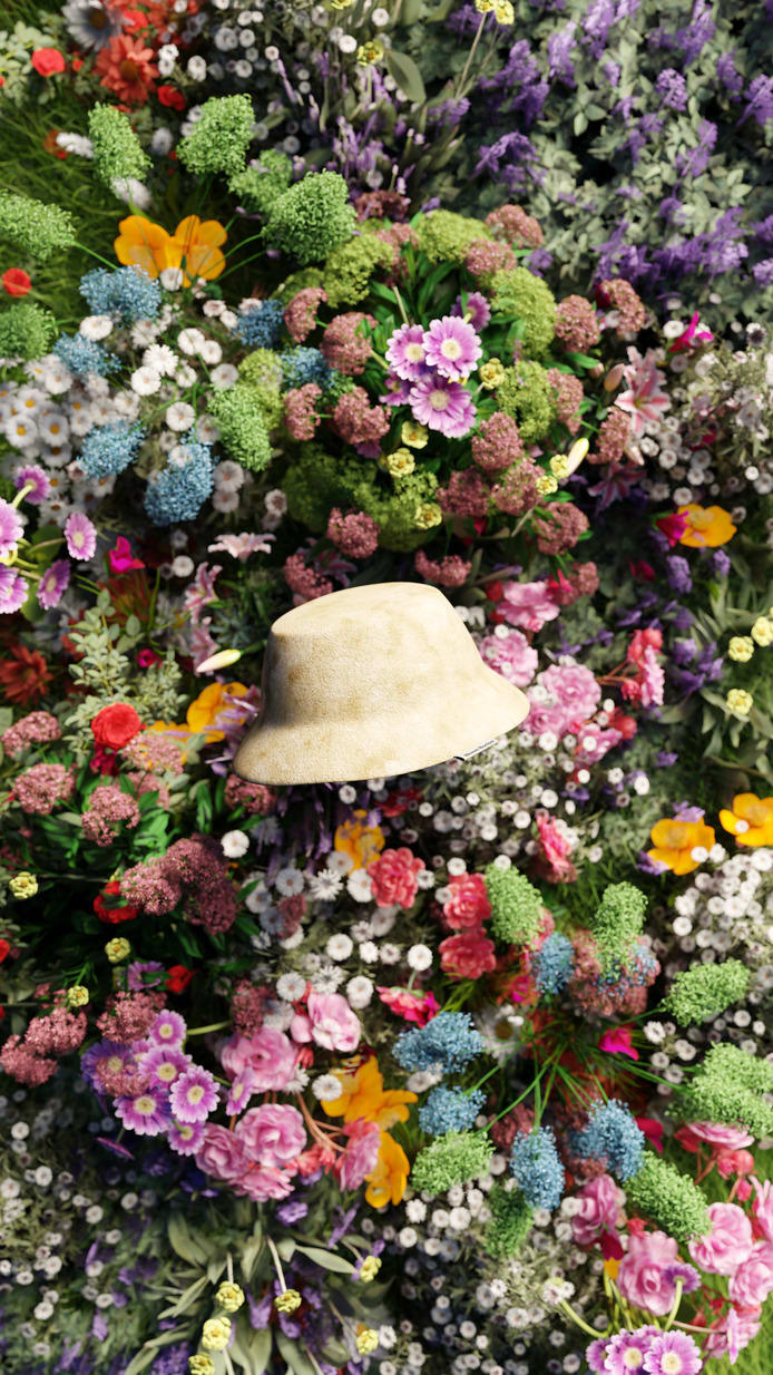 A bucket hat in a neutral beige color, made out of linen, floating in front of blooming wildflowers.