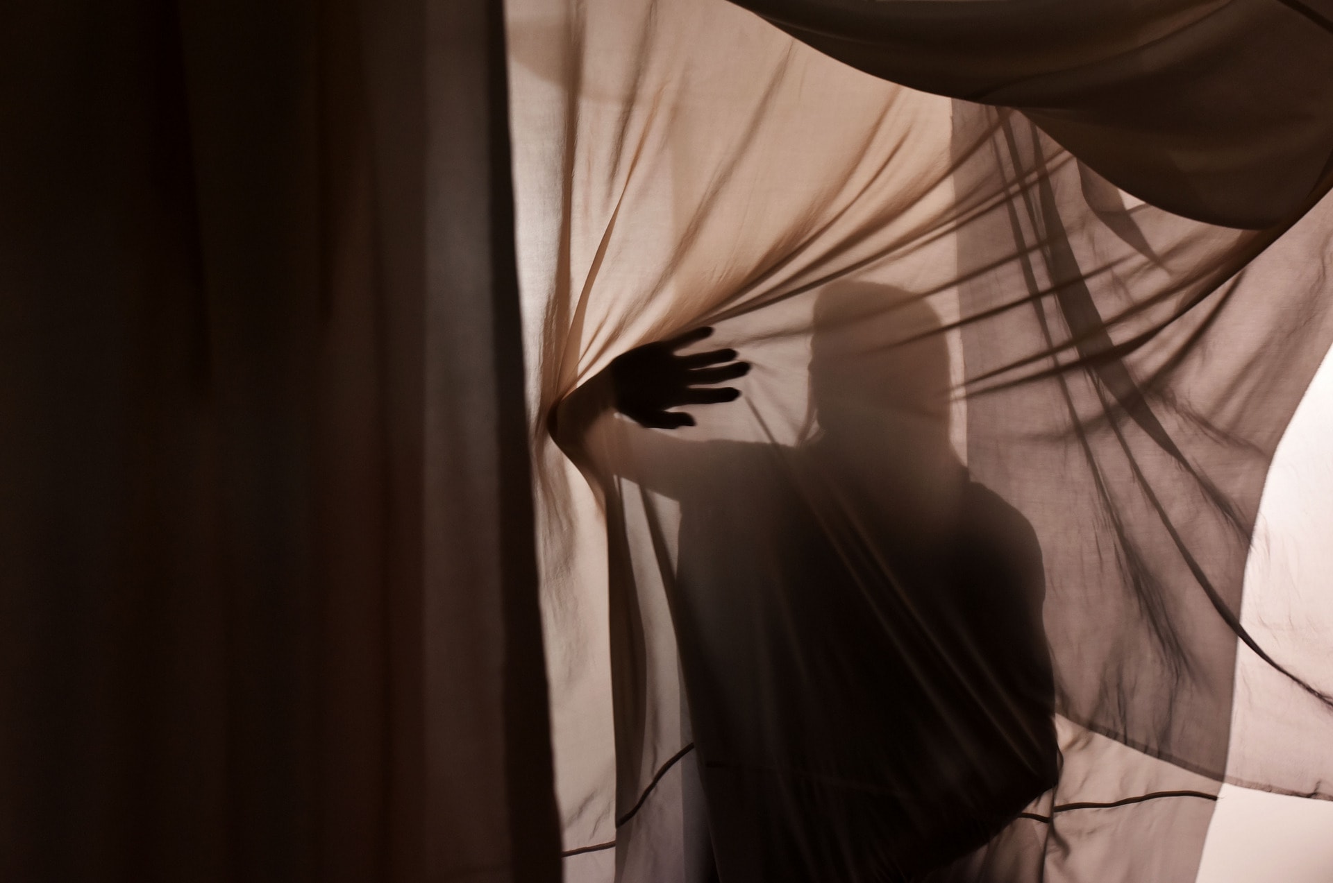 silhouette of dancer pushing through the layers of translucent silk fabric 