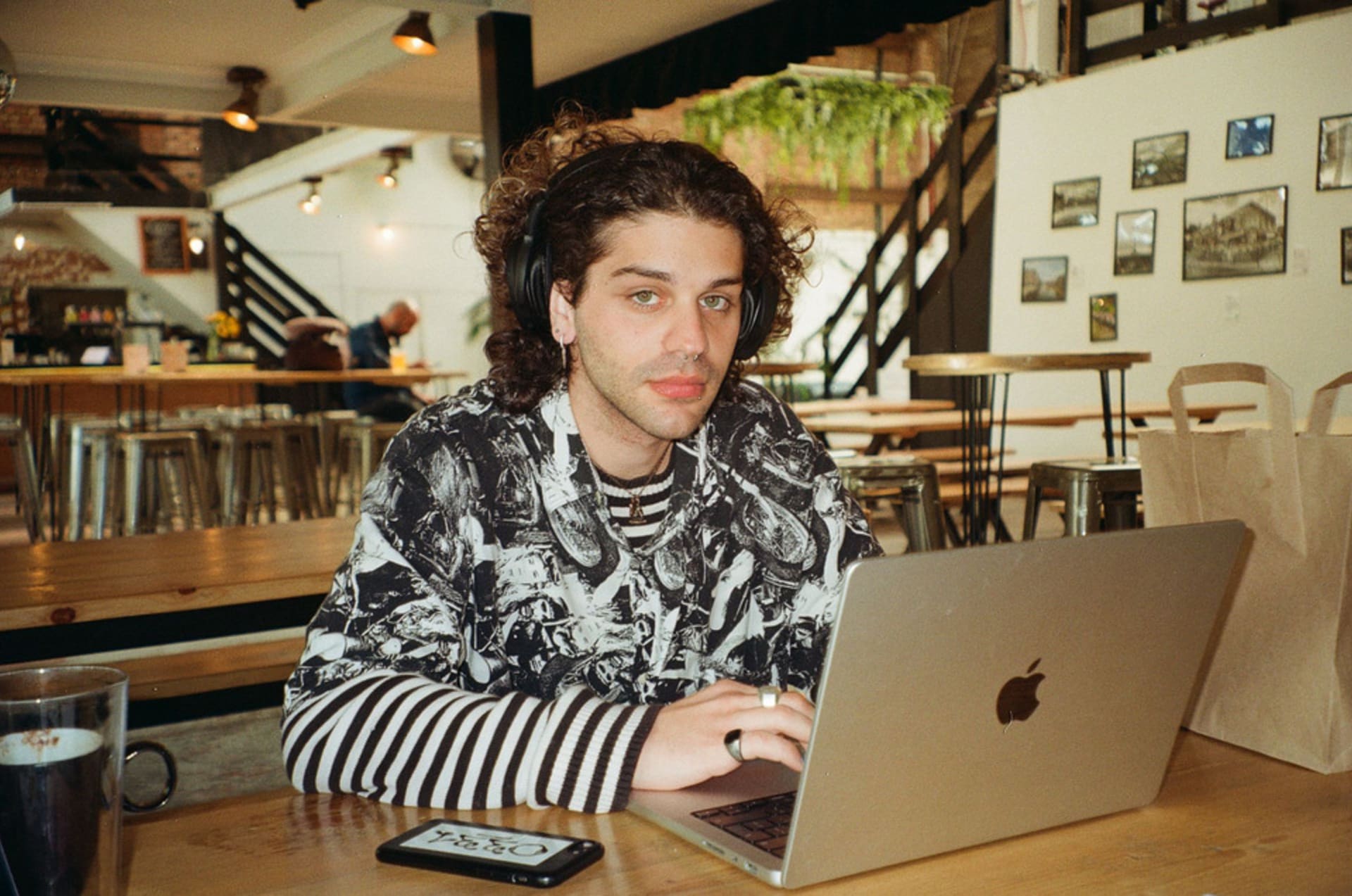 Photo of the artist working on a MacBook at a cafe.