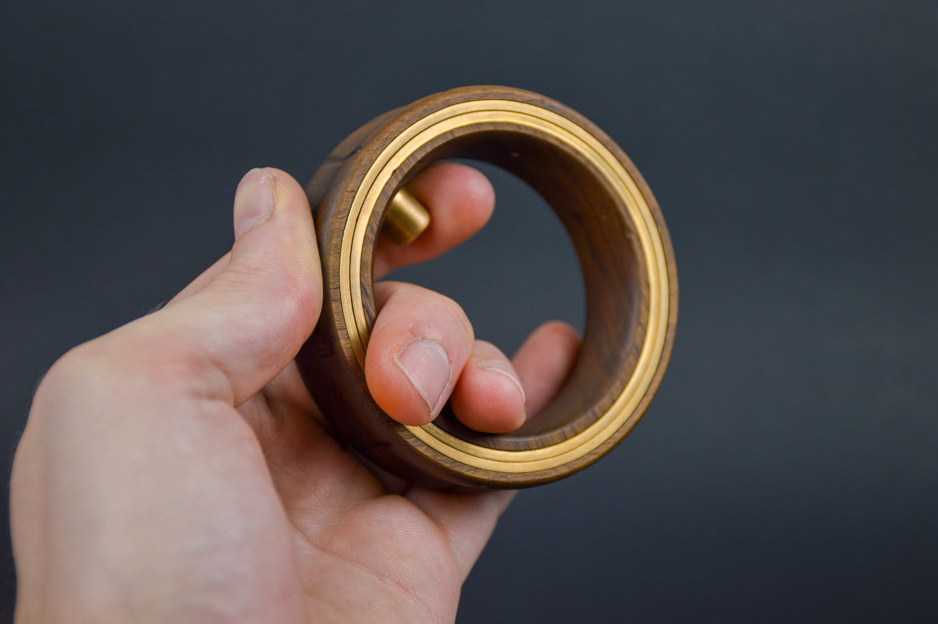 A walnut and brass ring being held