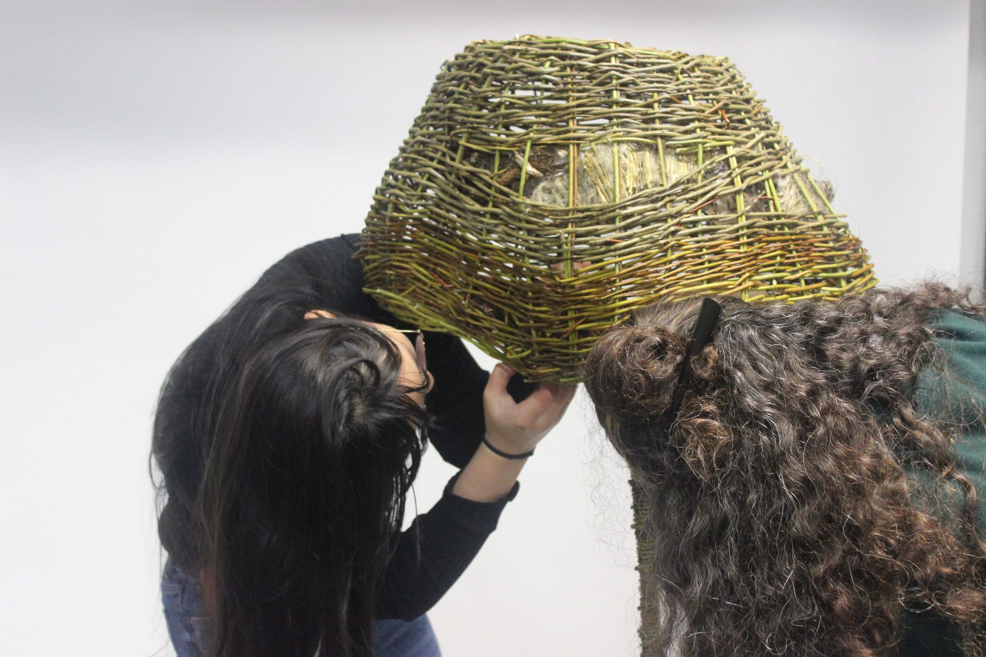 Two women looking under lampshade to secure to the base of the lamp