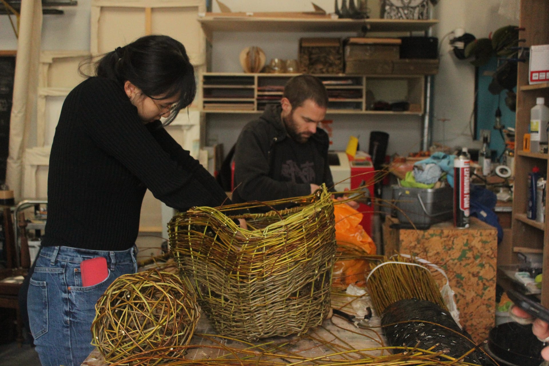Woman and man working on lamp and lampshade using willow in a studio environment