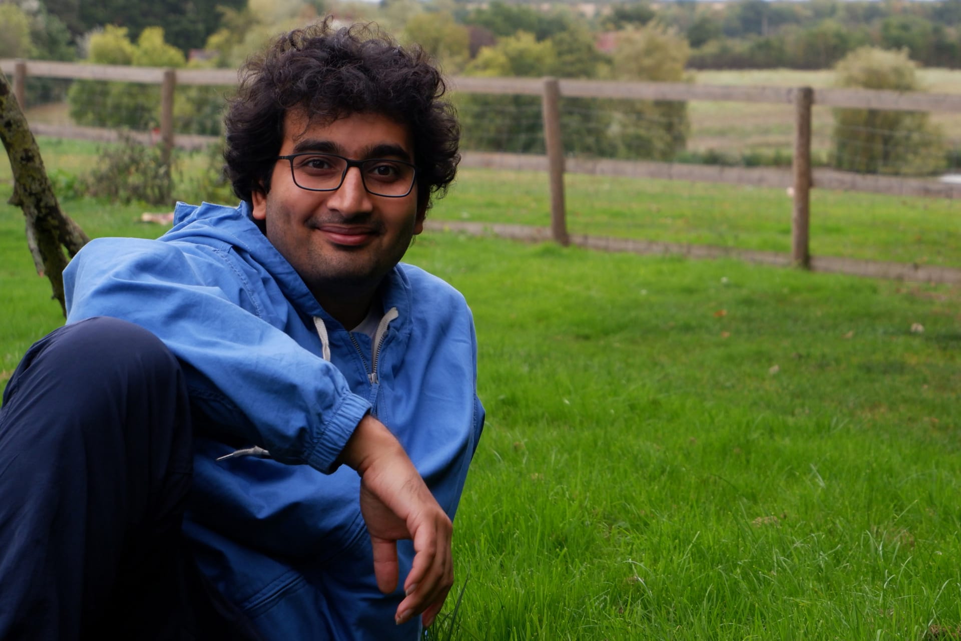An image of Janmejay (me) sitting on the grass in a garden, smiling