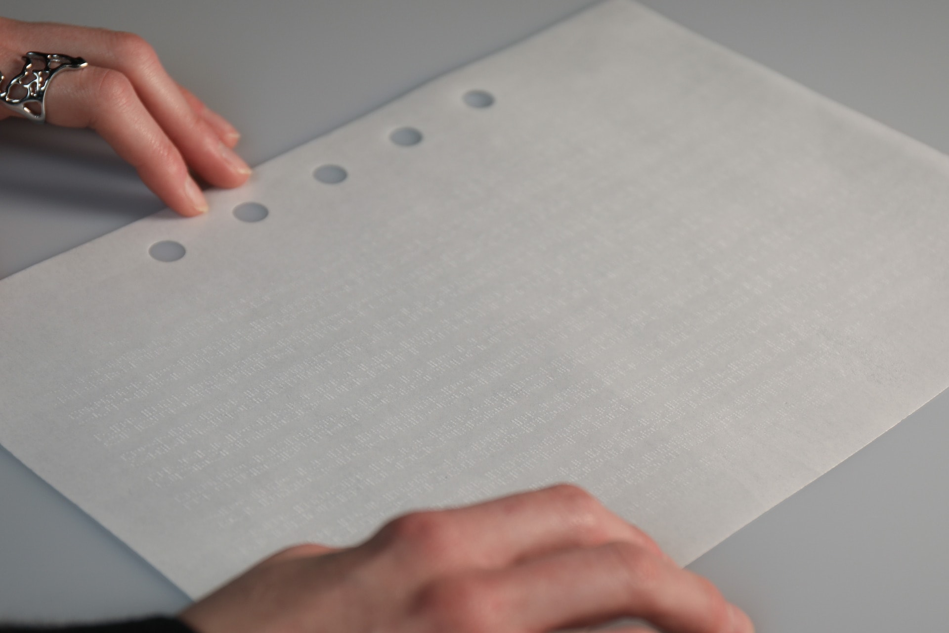 Photograph of two hands gently touching the edible booklet. Space code only visible with use of light