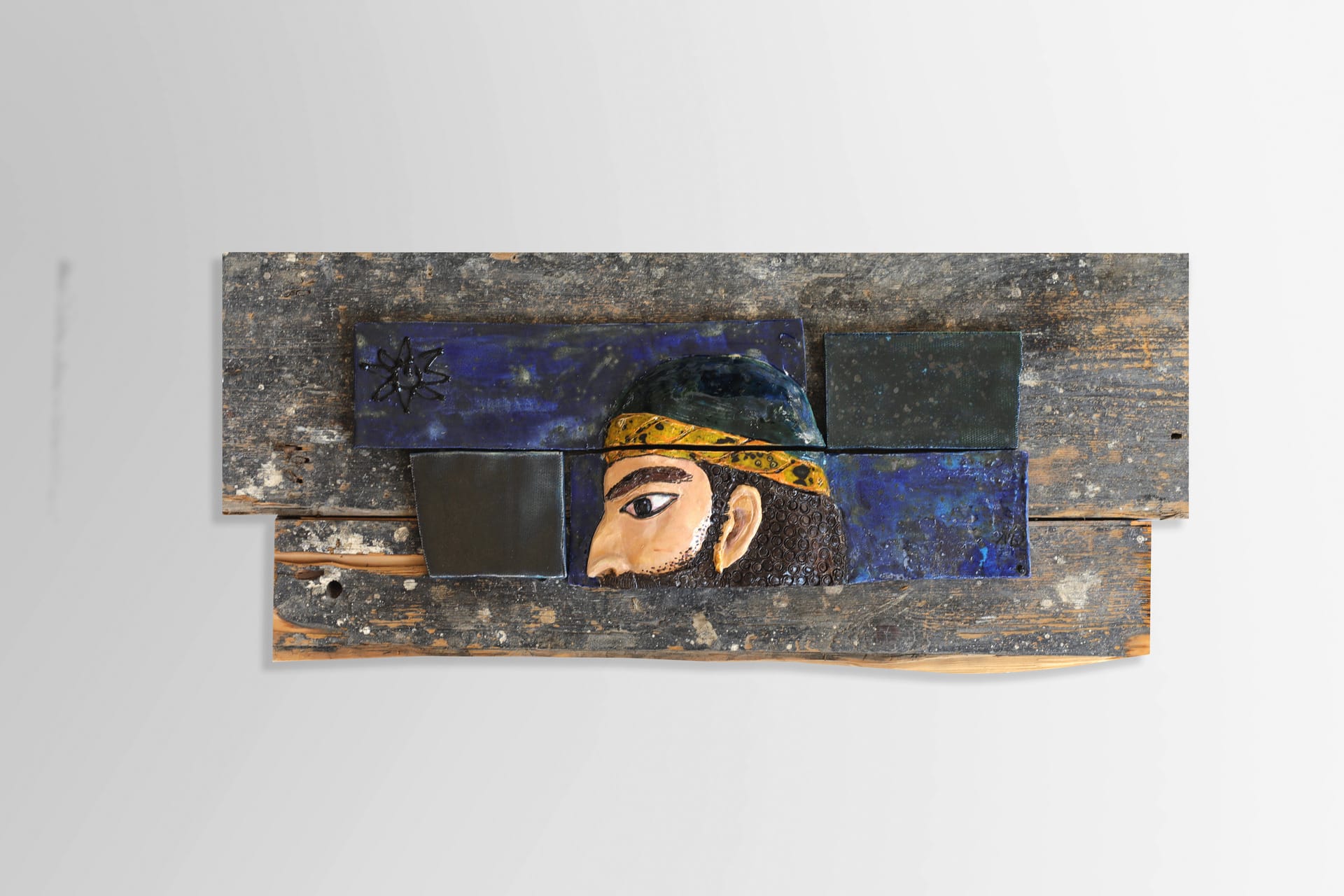 A piece of relief. Warrior head on the Victorian wooden floorboard. Souvenir.