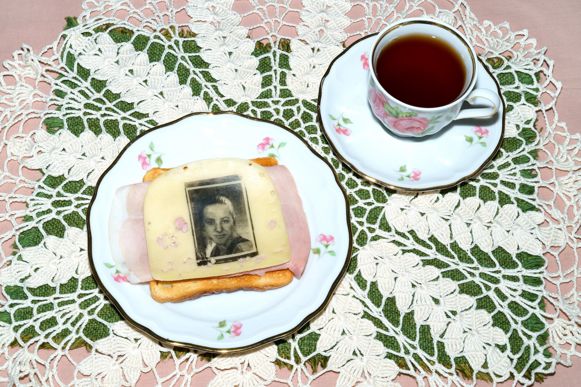 A portrait printed on a slice of cheese next to a cup of tea.