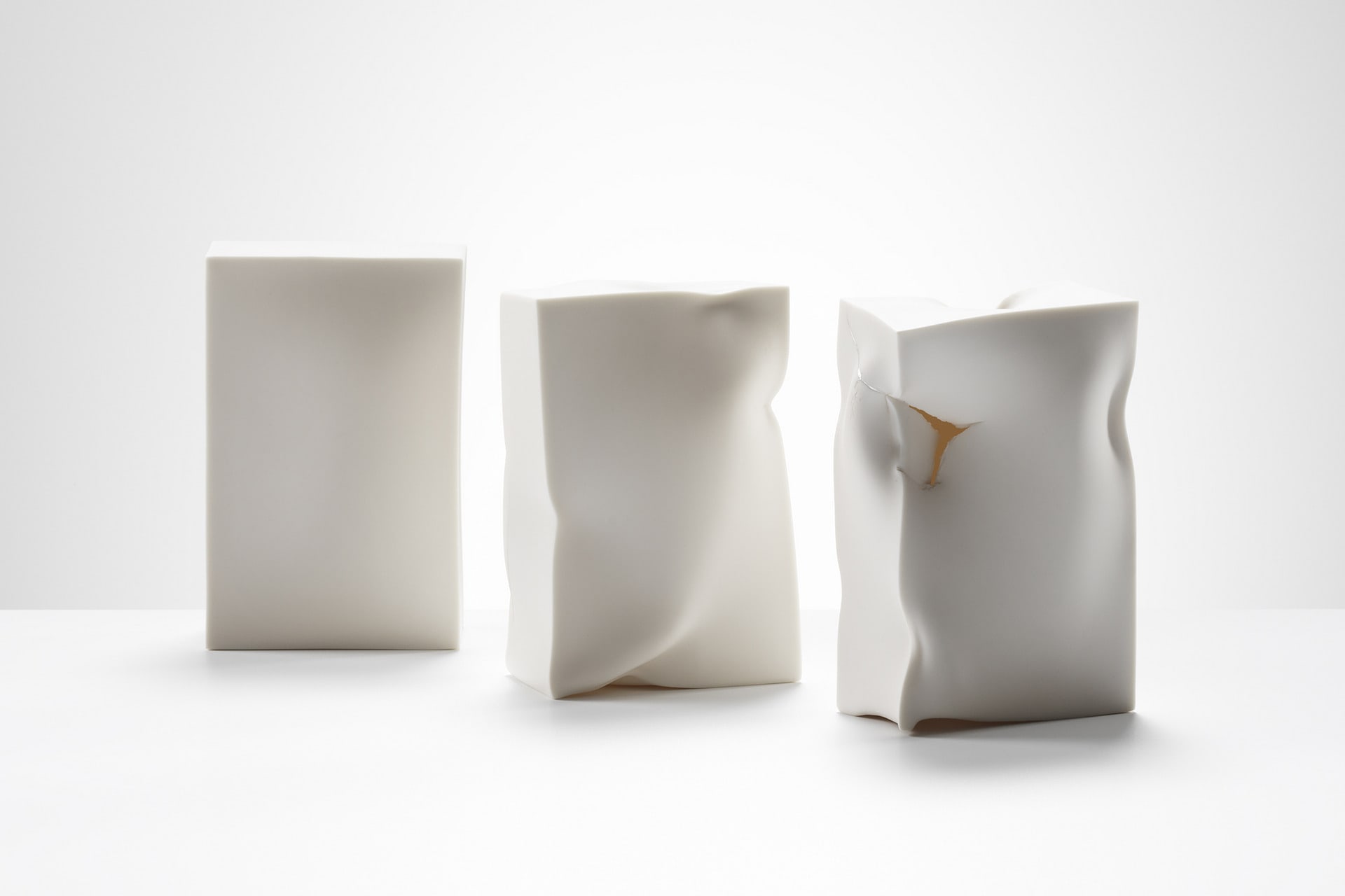 Three rectangular boxes of same size, in their original rigid form, distorted with fluid movements and disrupted.