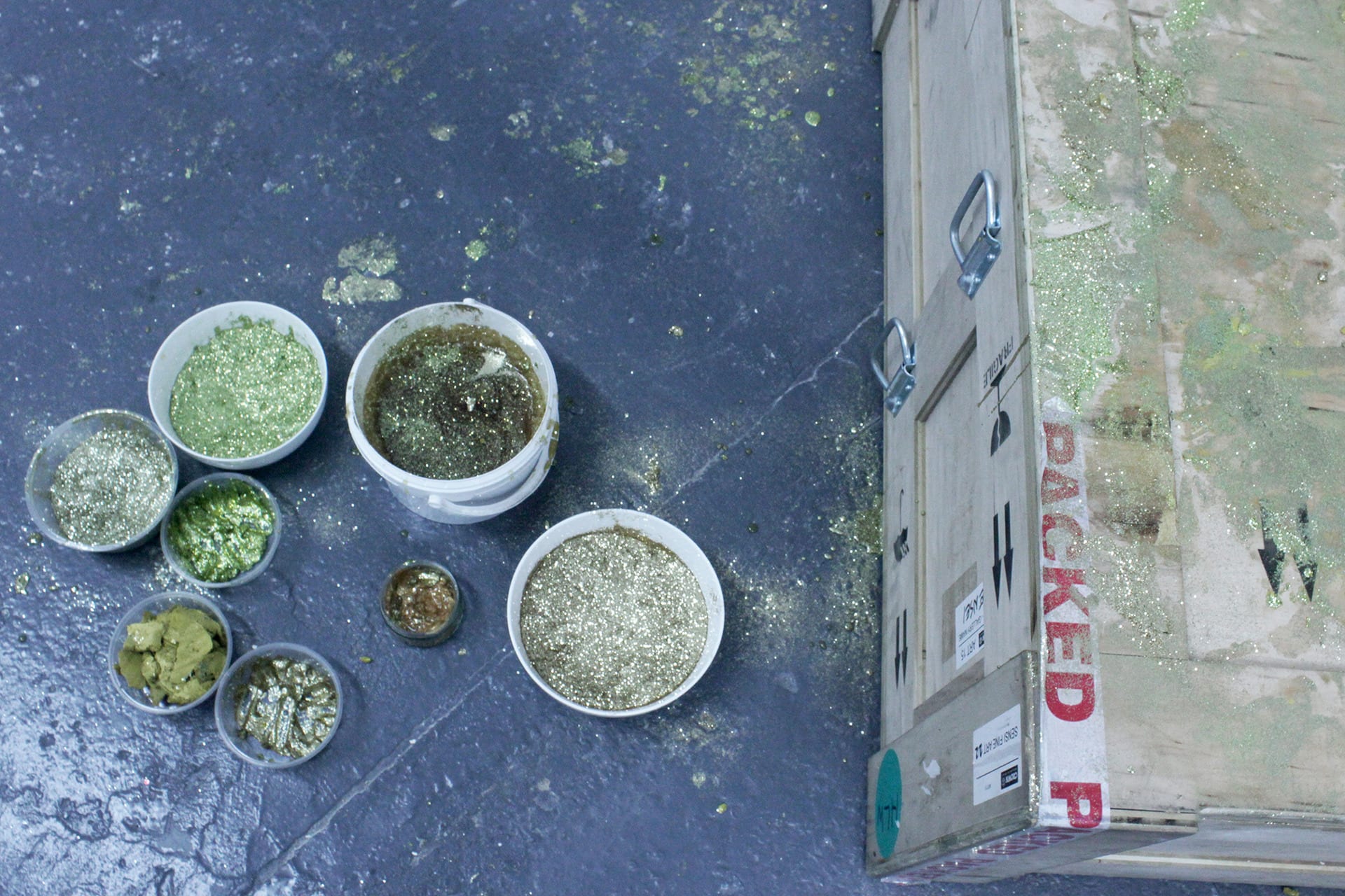 Bowls with glitter and honey placed right next to a wooden crate. 