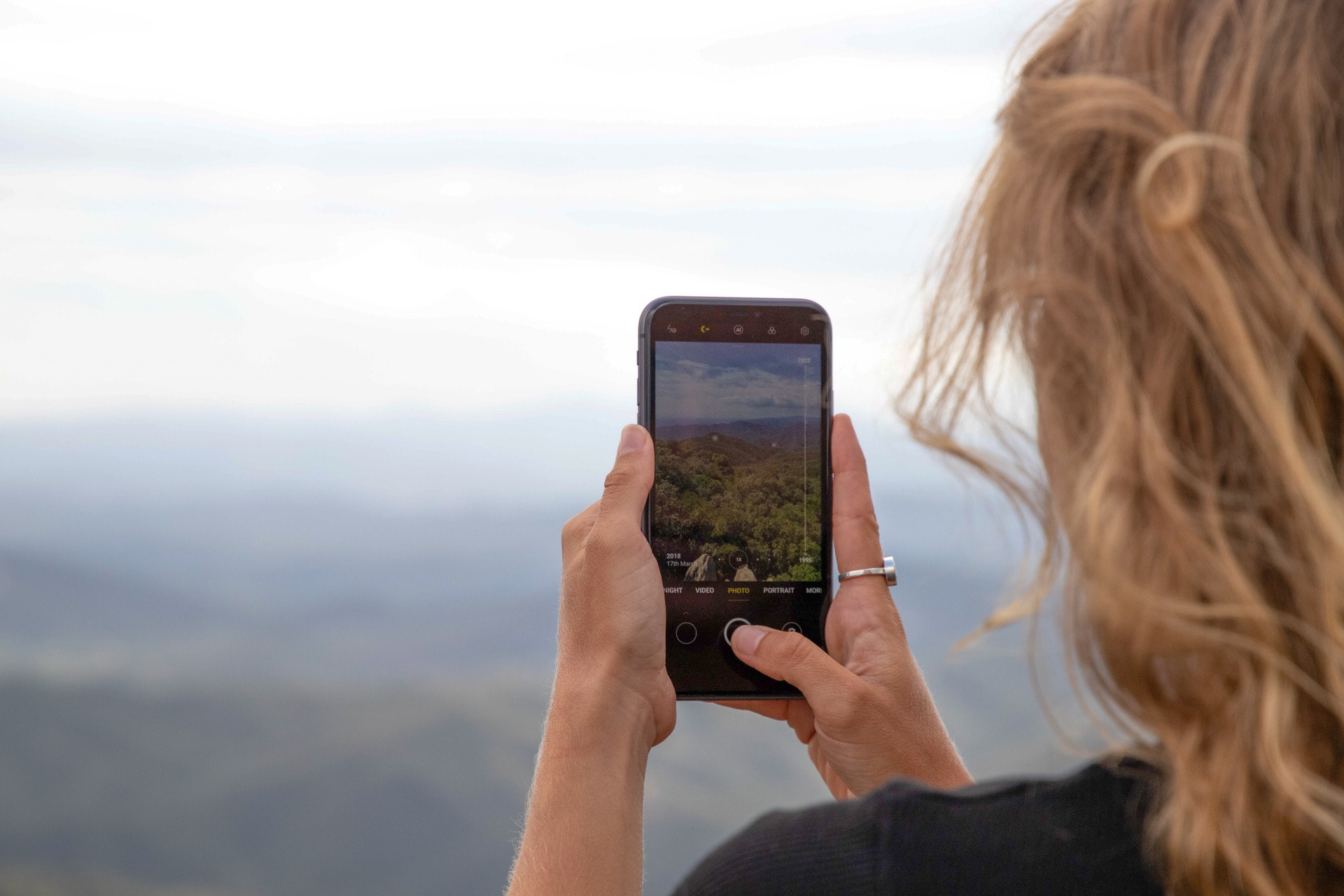 Girl taking a picture of a landscape with c-earth visible on the screen