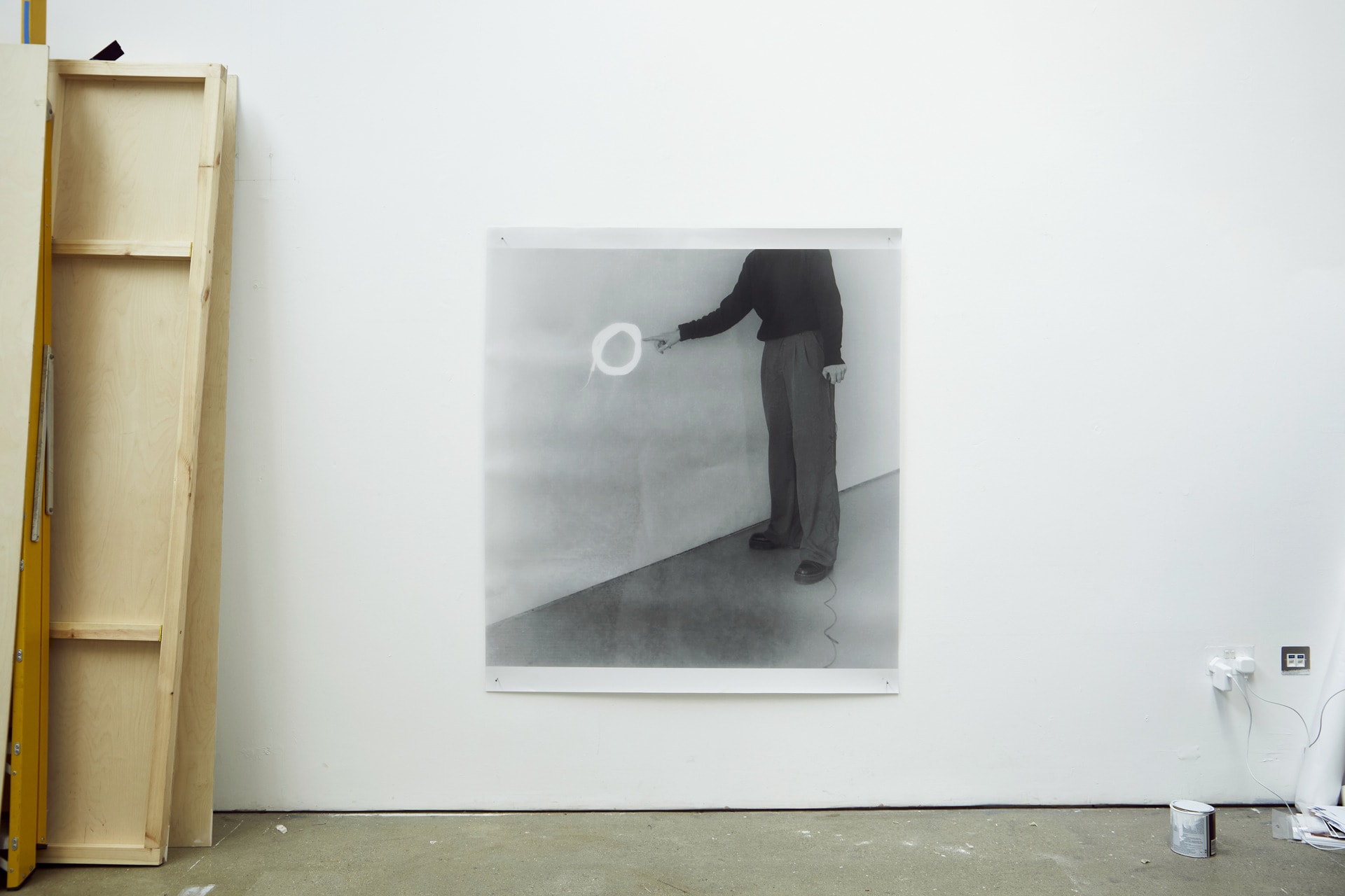 An installation of a black and white print in the studio, an analog self portrait pointing to a white circle