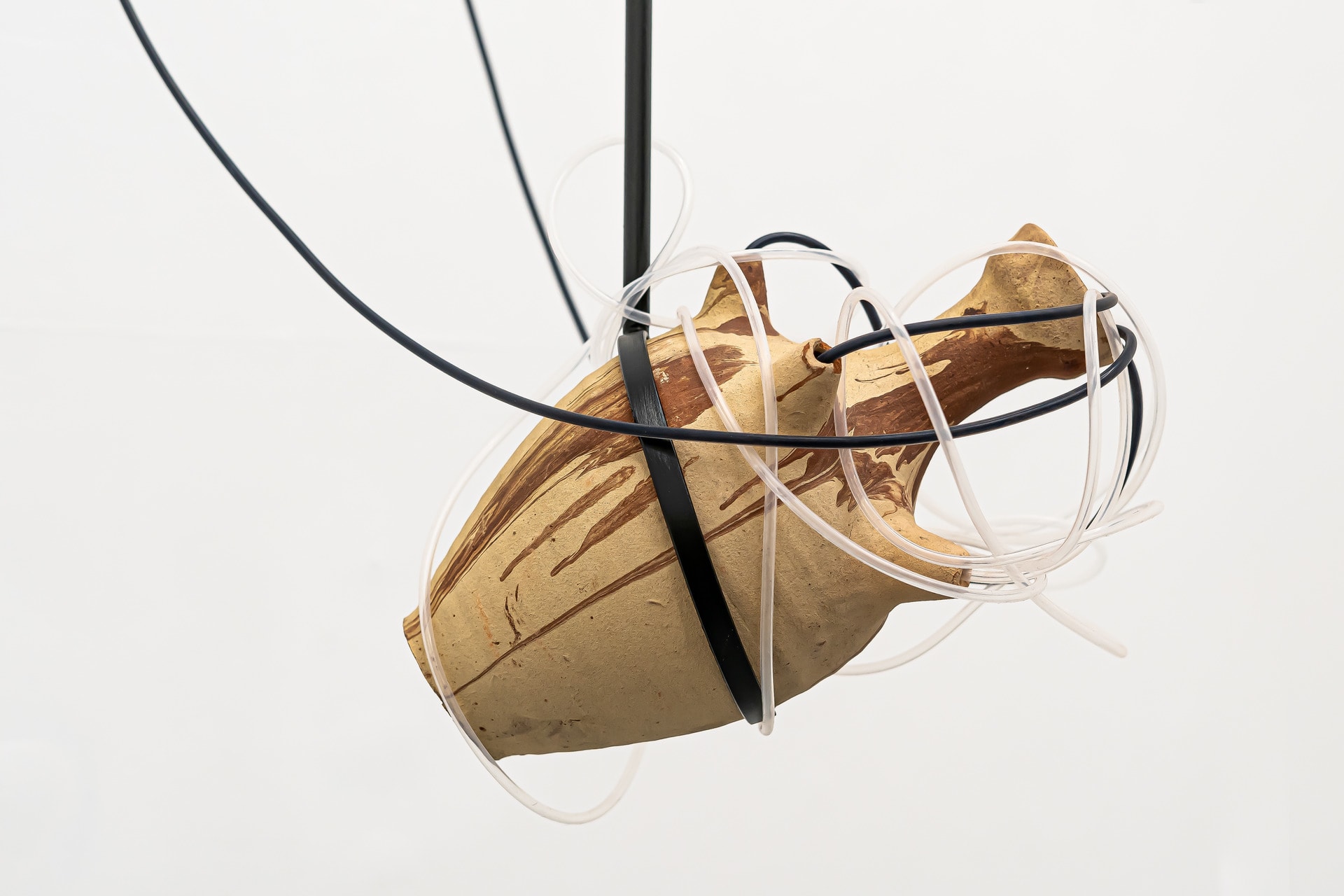 Water jug made of ceramic suspended with metal armature and a water system flowing through the openings of the pot