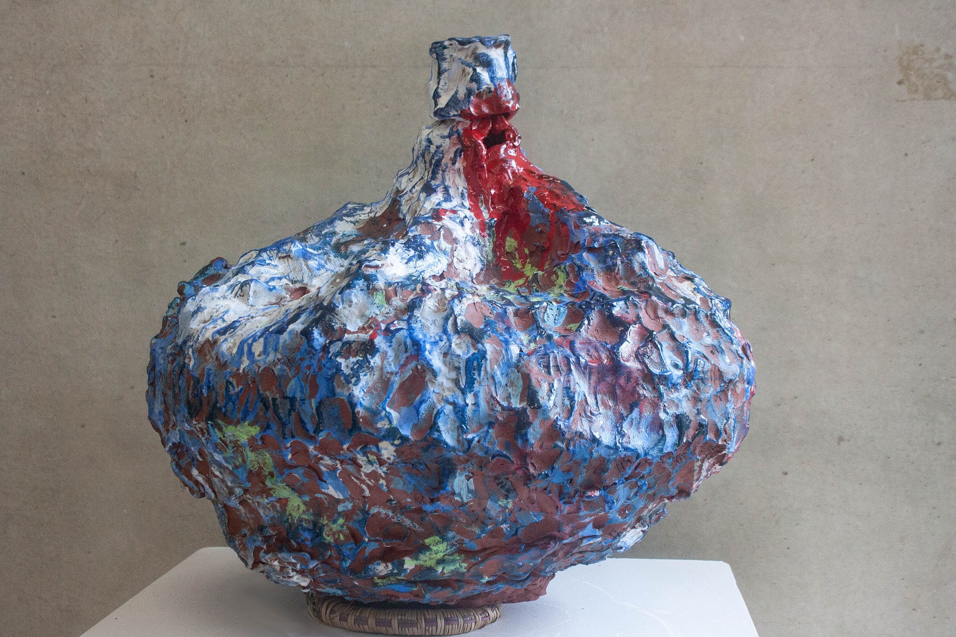 wide based ceramic sculptural pot with narrow neck vividly decorated blue and white with some red