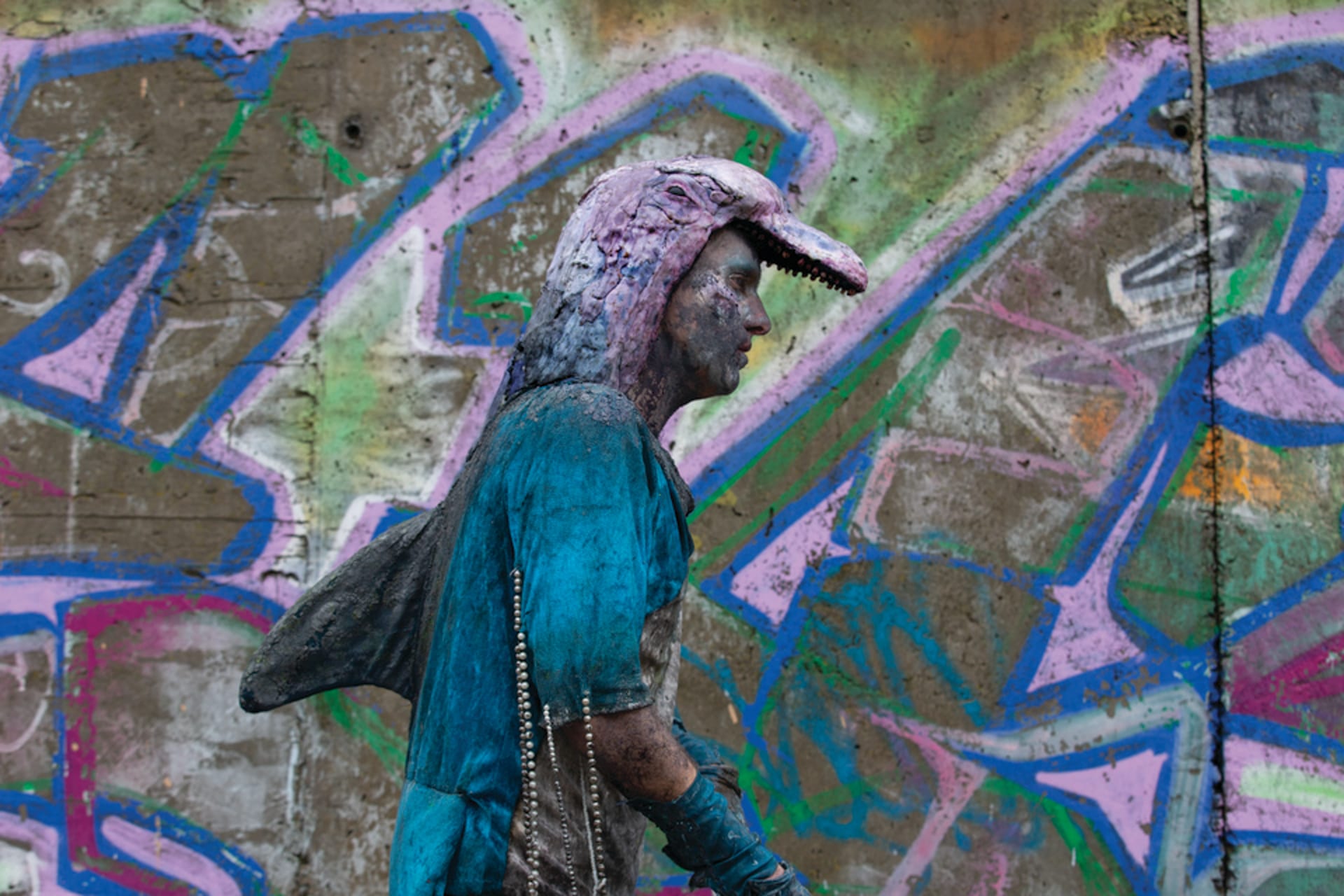 man in dolphin costume walking past graffiti 