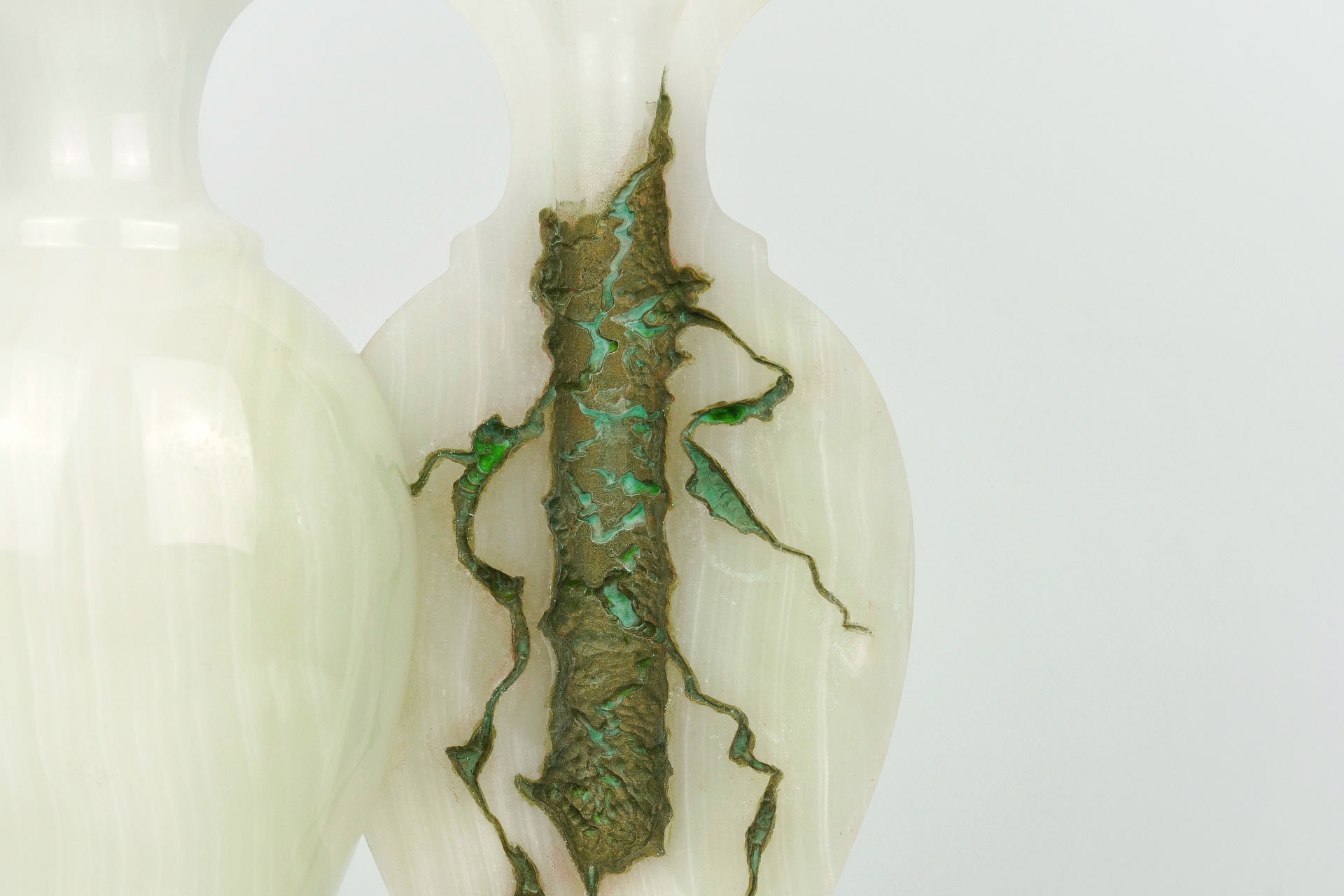 The interior of the jade vase is carved with tattered texture and covered with brass paint oxidized to produce a green patina.