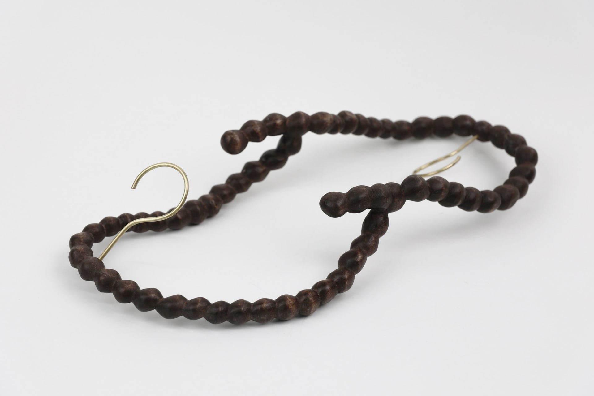 Two strings of wood-carved pearls connected to each other with two hooks in the middle of each string representing the hangers.