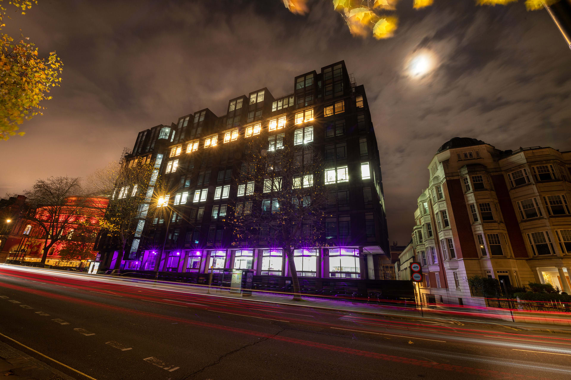 A photo of the RCA's Kensington Campus lit up with purple lights on the ground floor.