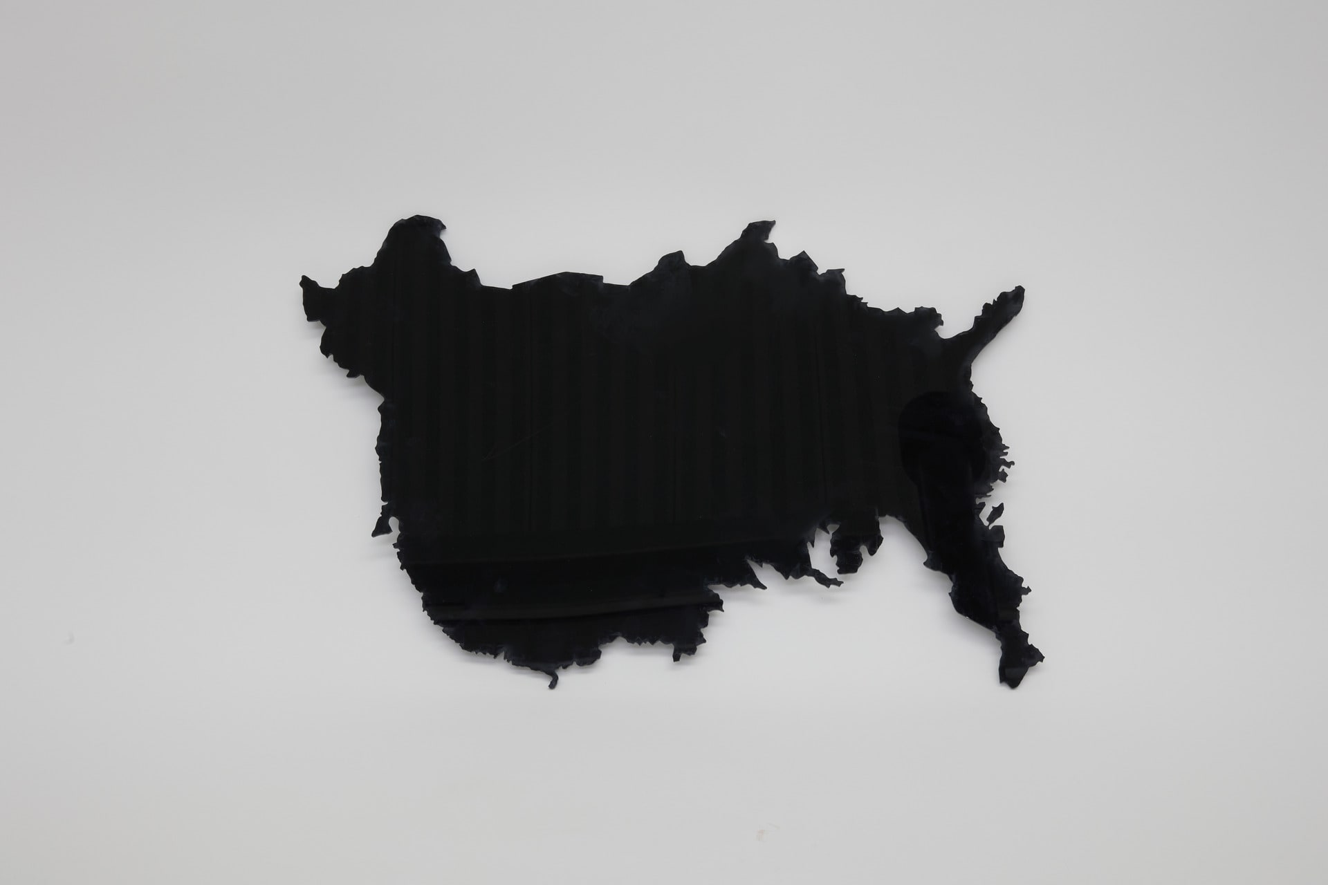 A black acrylic sheet cut in the shape of the China and USA maps overlapped to create an ambiguous shape.