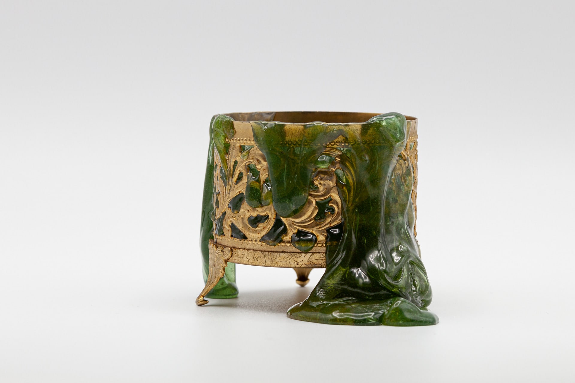 This image depicts a green substance melting down over an ornamental bronze base.