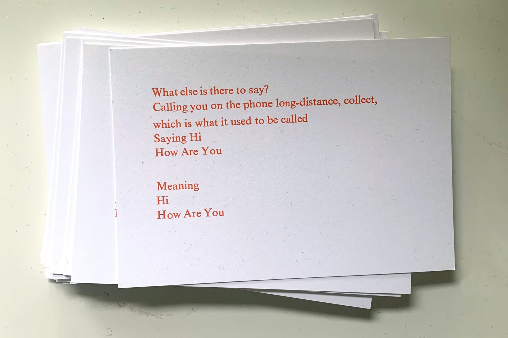 A stack of postcards printed with orange ink. The writing on them is a short poem. 