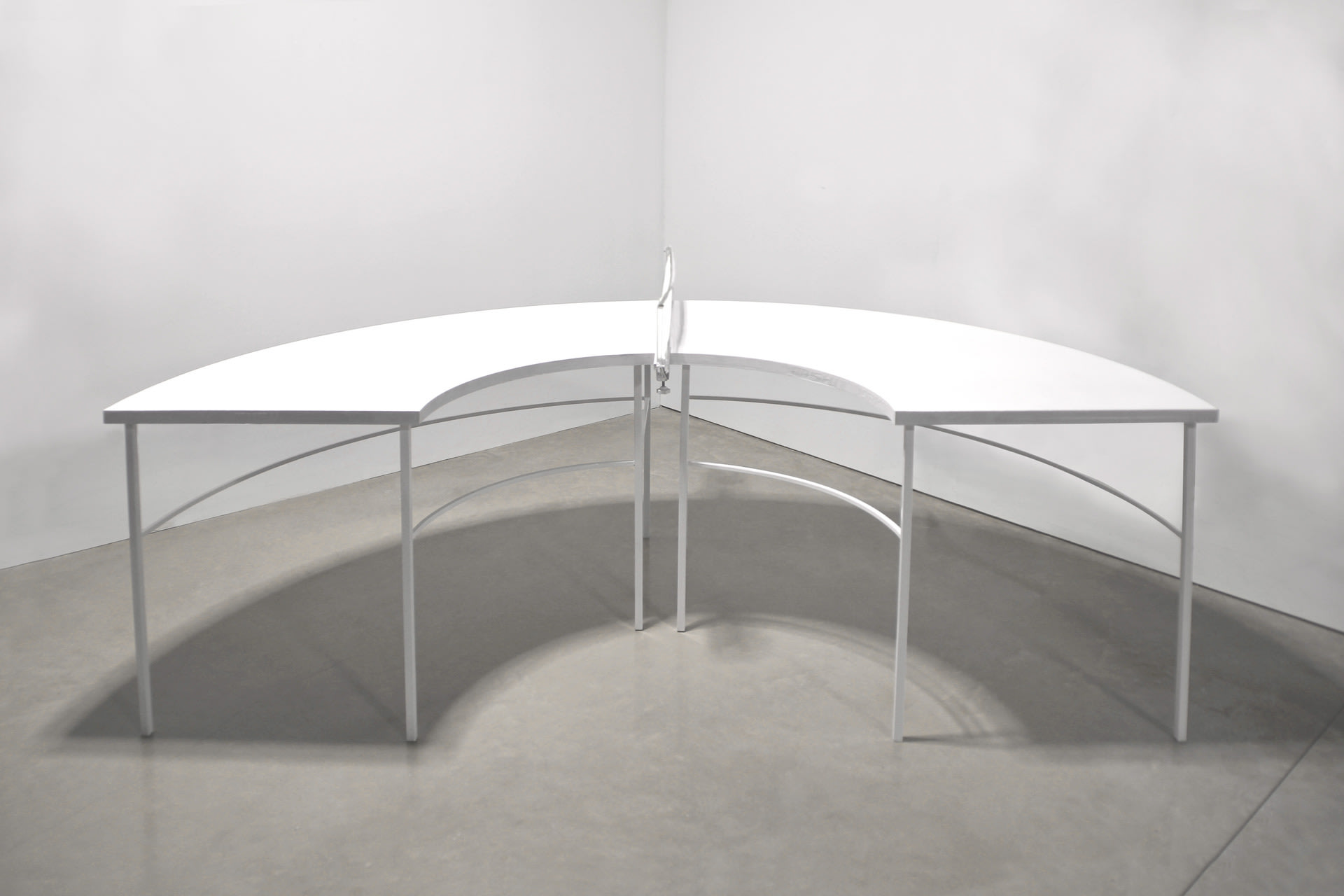 A ping pong table is built in semi circle and painted in white.