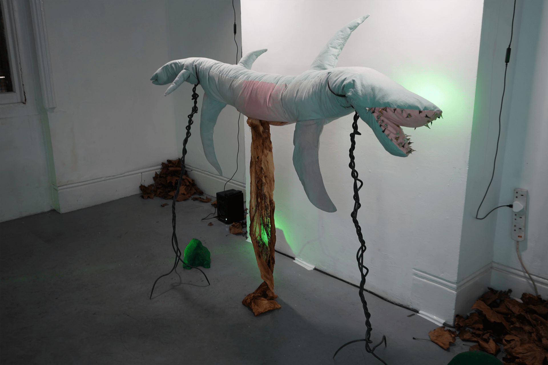 Soft sculpture of a shark on gothic metal stands.