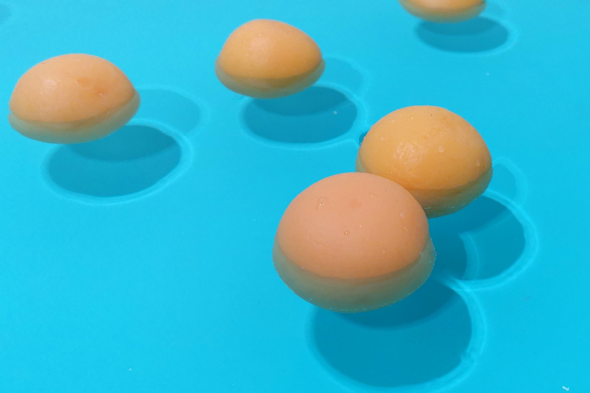 Casts of oranges floating in a blue pool