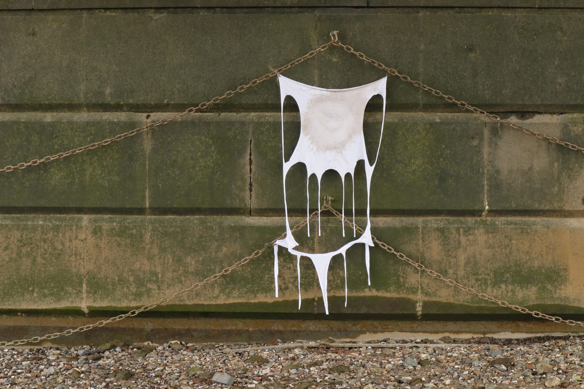 Skin of the River Thame, 2023. cotton knitted T-shirt fabric, mud dye. Hanging from the wall under Battersea Bridge at low tide.