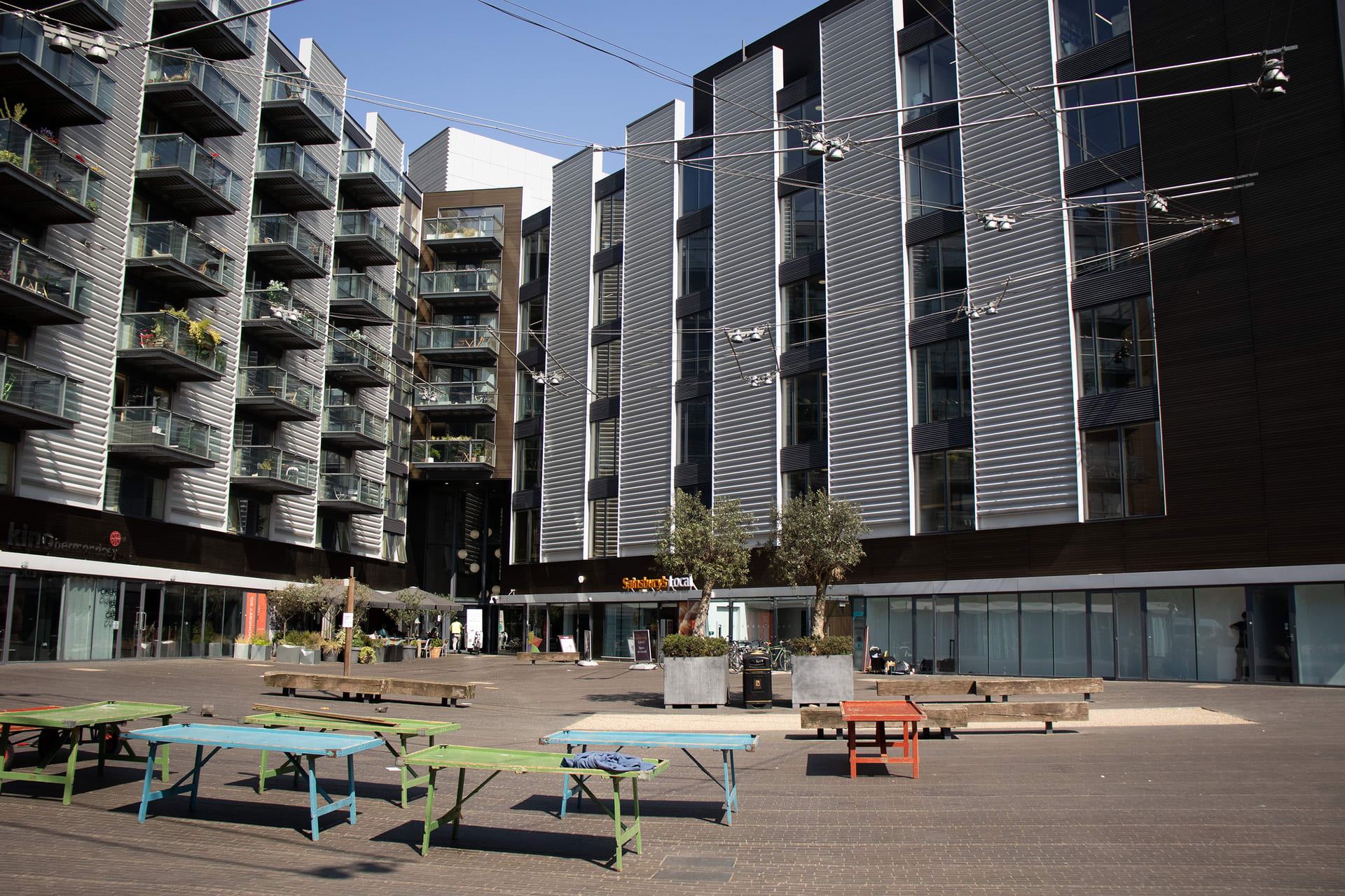 empty market stalls sit agains the backdrop of modern flats, looming over The stalls are isolated below