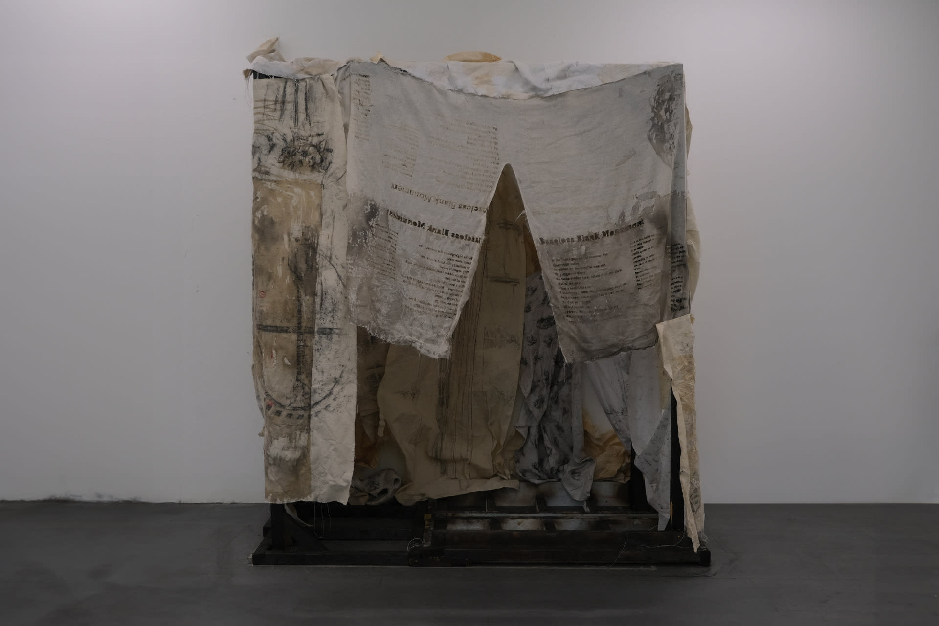 Rubbed fabrics are hung on fire-burned wooden frames, like a kind of dilapidated monument