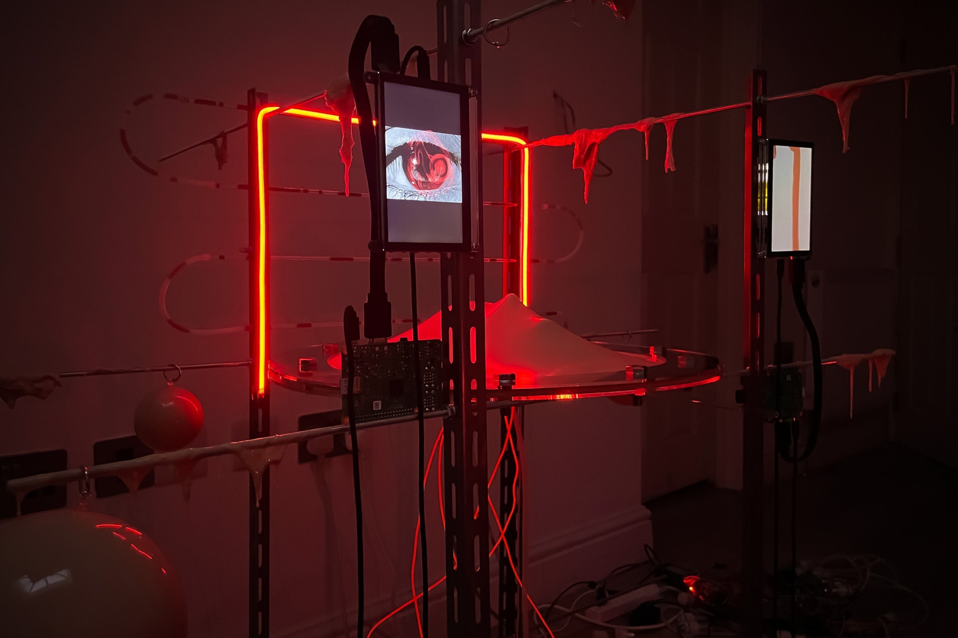 A futuristic art installation consisting of a metal frame, silicone and two screens.
