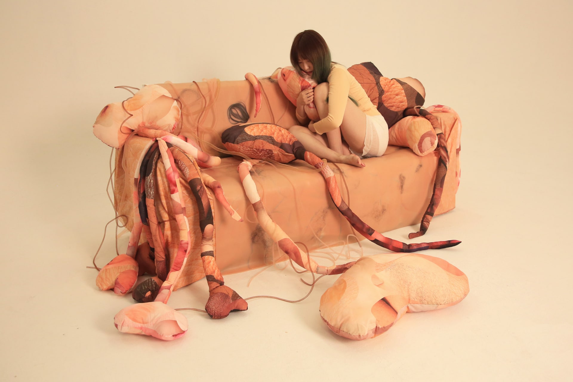 Skin Hunger-To Get Under The Skin explores tactile receptors with fabric sculptures and silicone-made human skin on a sofa. 