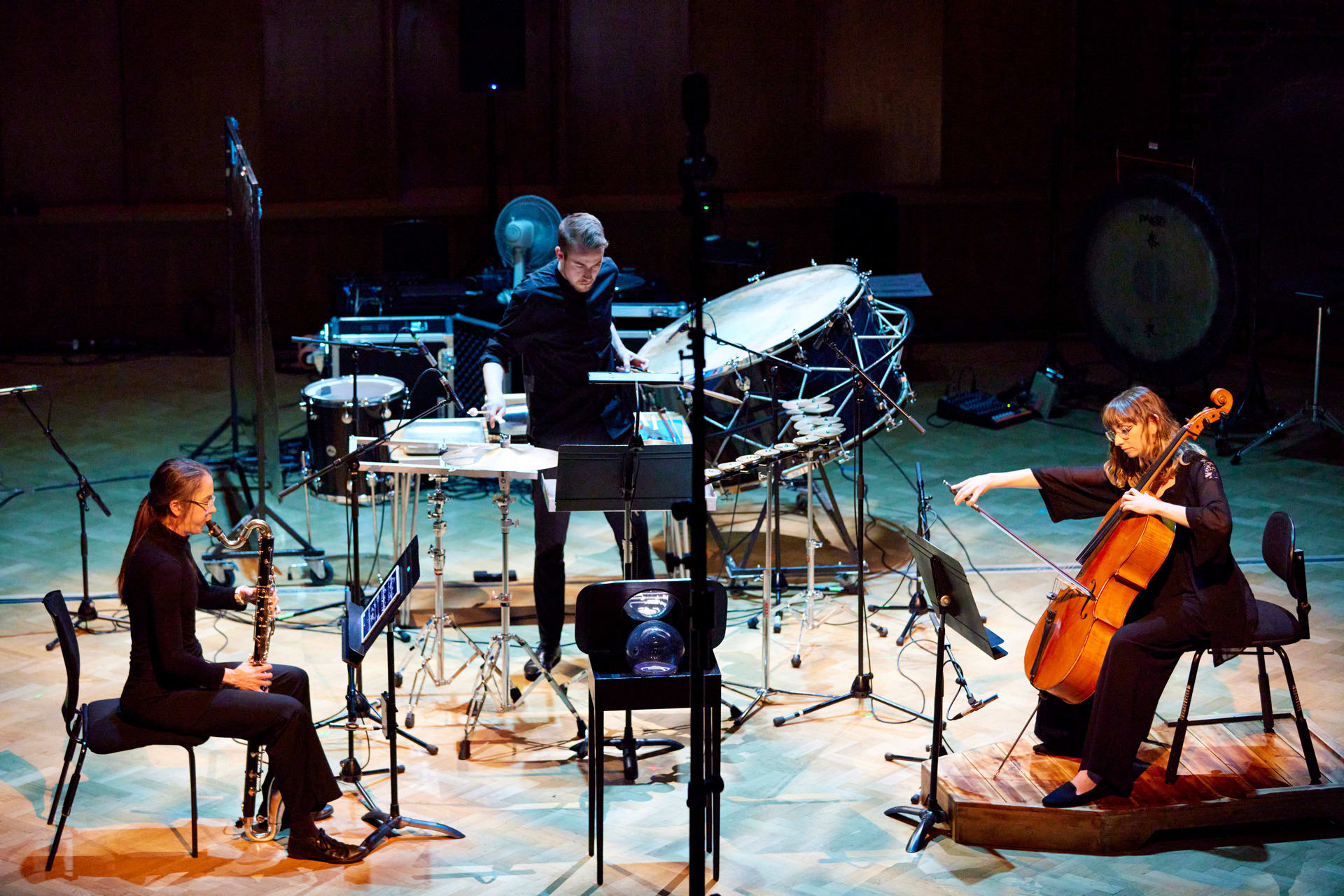 A chamber trio are arranged around a crystal-ball sculpture. 