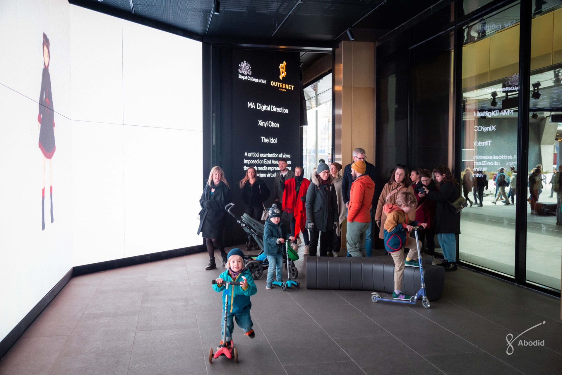 A bustling exhibition of a graduation project featuring a large screen displaying the creator's work.