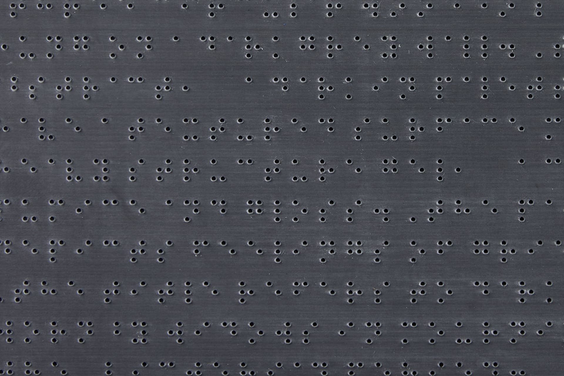 A close up of laser etched braille into black acrylic.