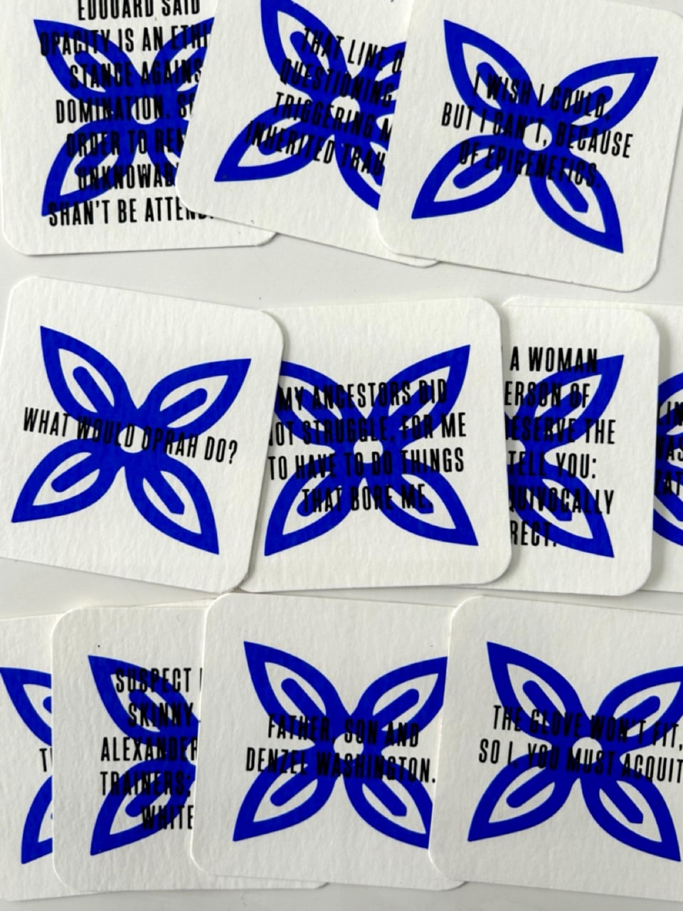 Black text in capitals, upon a dark blue floral symbol on square white cards