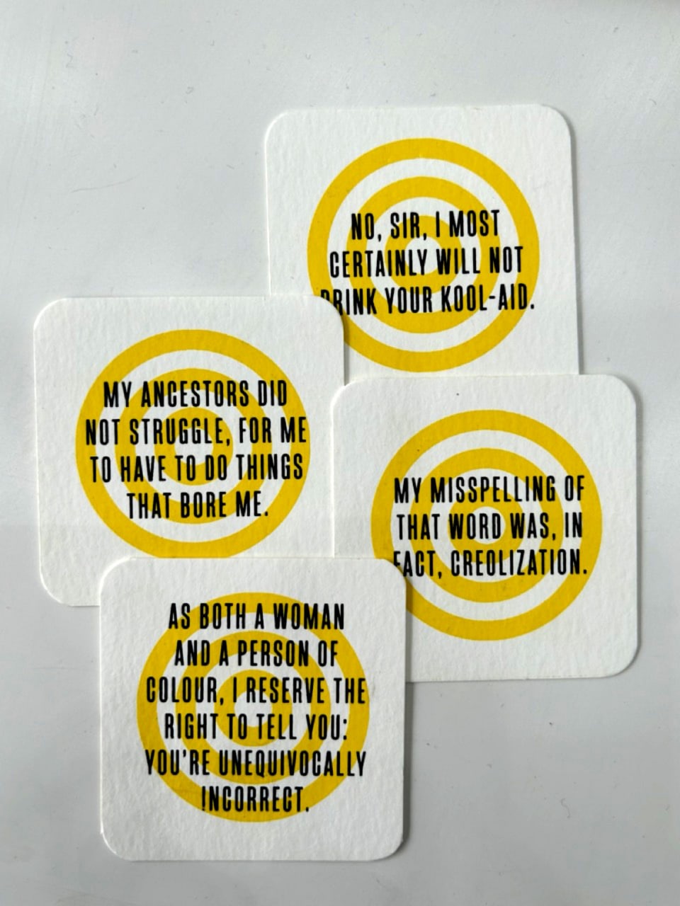 Black text in capitals, upon an a yellow symbol made of concentric circles on square white cards