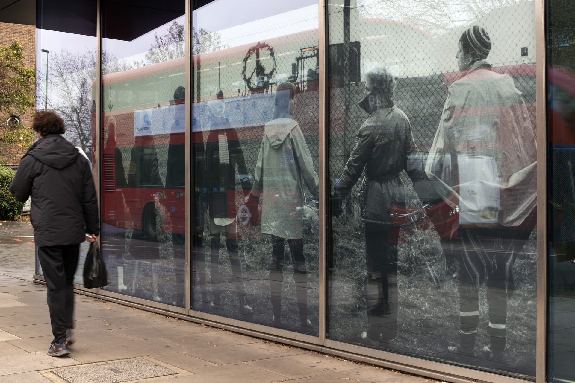 Person walking alongside glass windows with photographs of women holding hands.